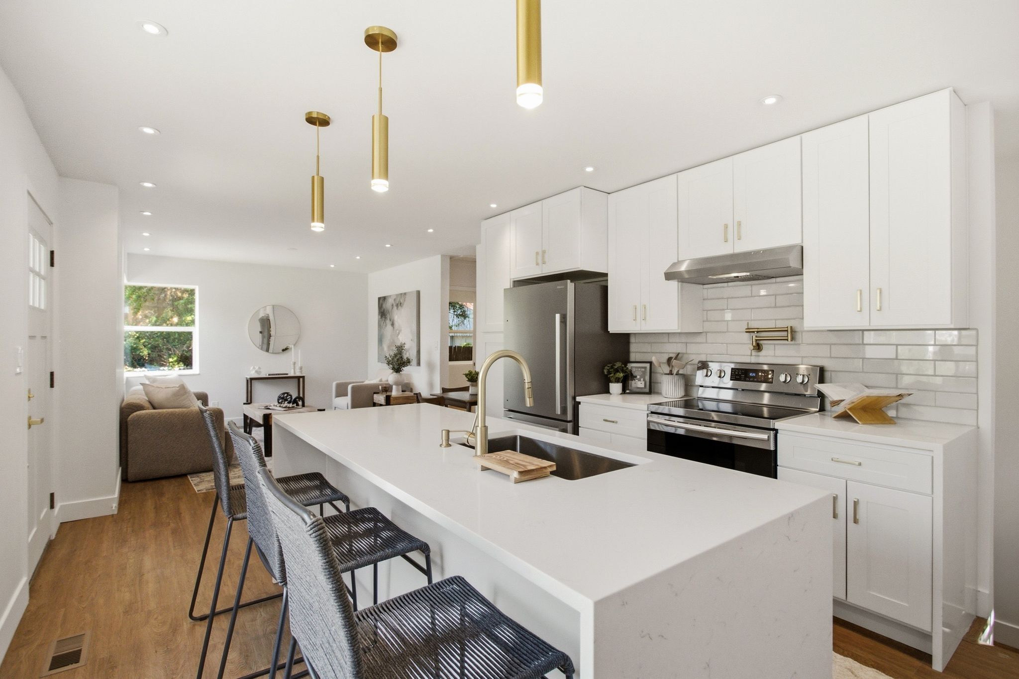 Modern kitchen featuring a waterfall-edge island with an undermount sink and gold-finish faucet