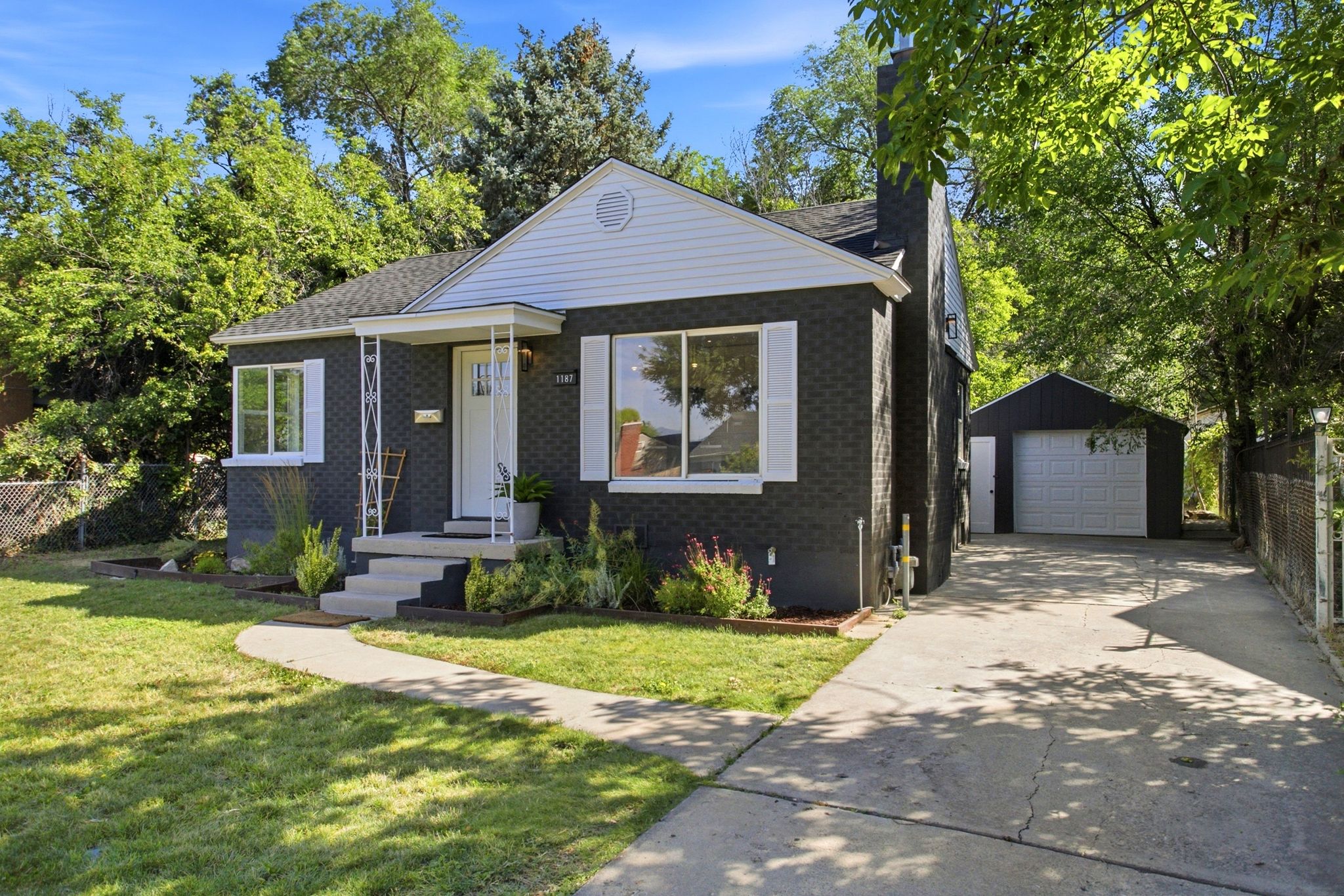 Contemporary exterior featuring dark brick, white shutters, and a covered entry