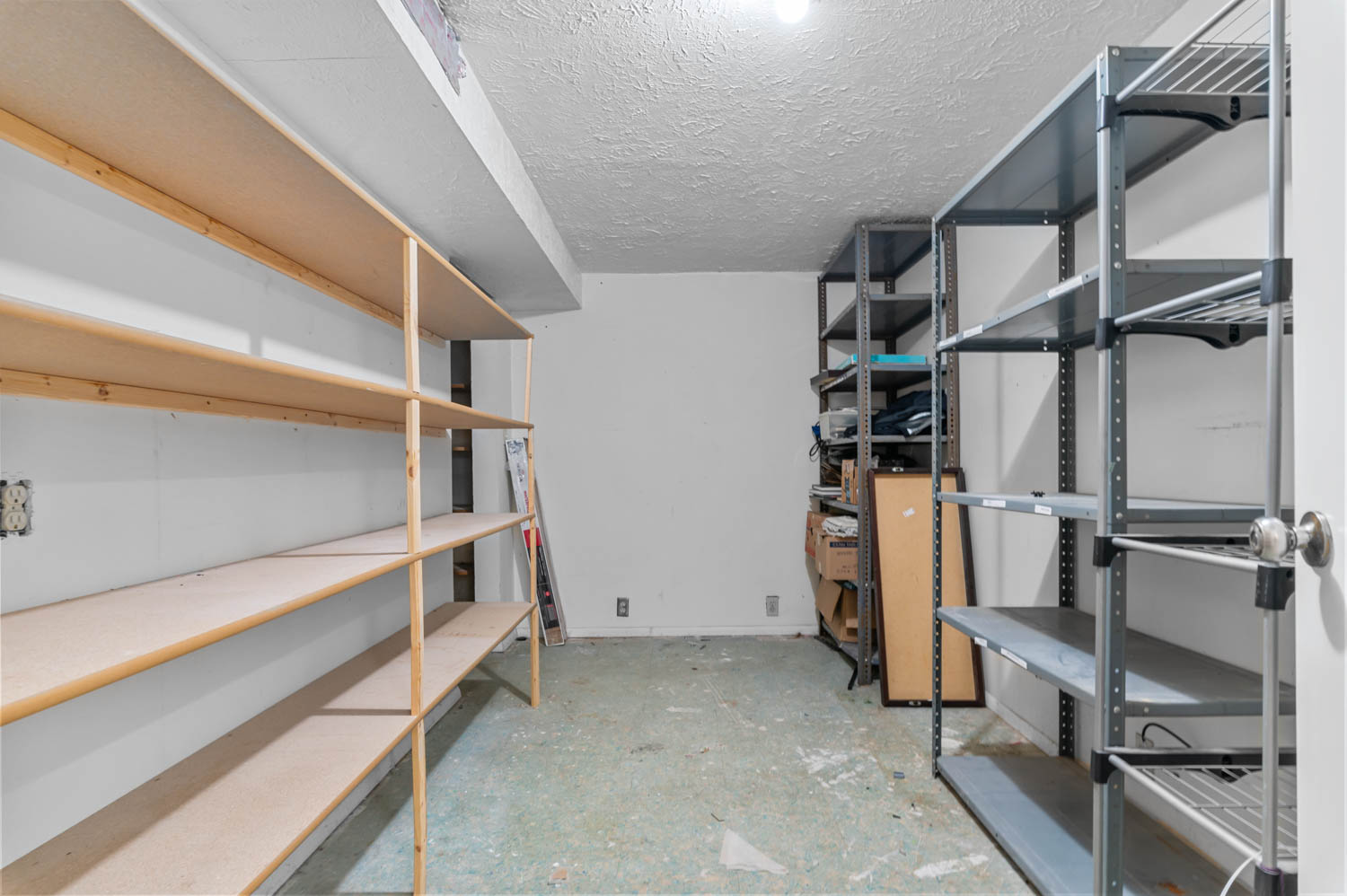 Utility room featuring extensive built-in shelving, durable concrete flooring, and overhead lighting