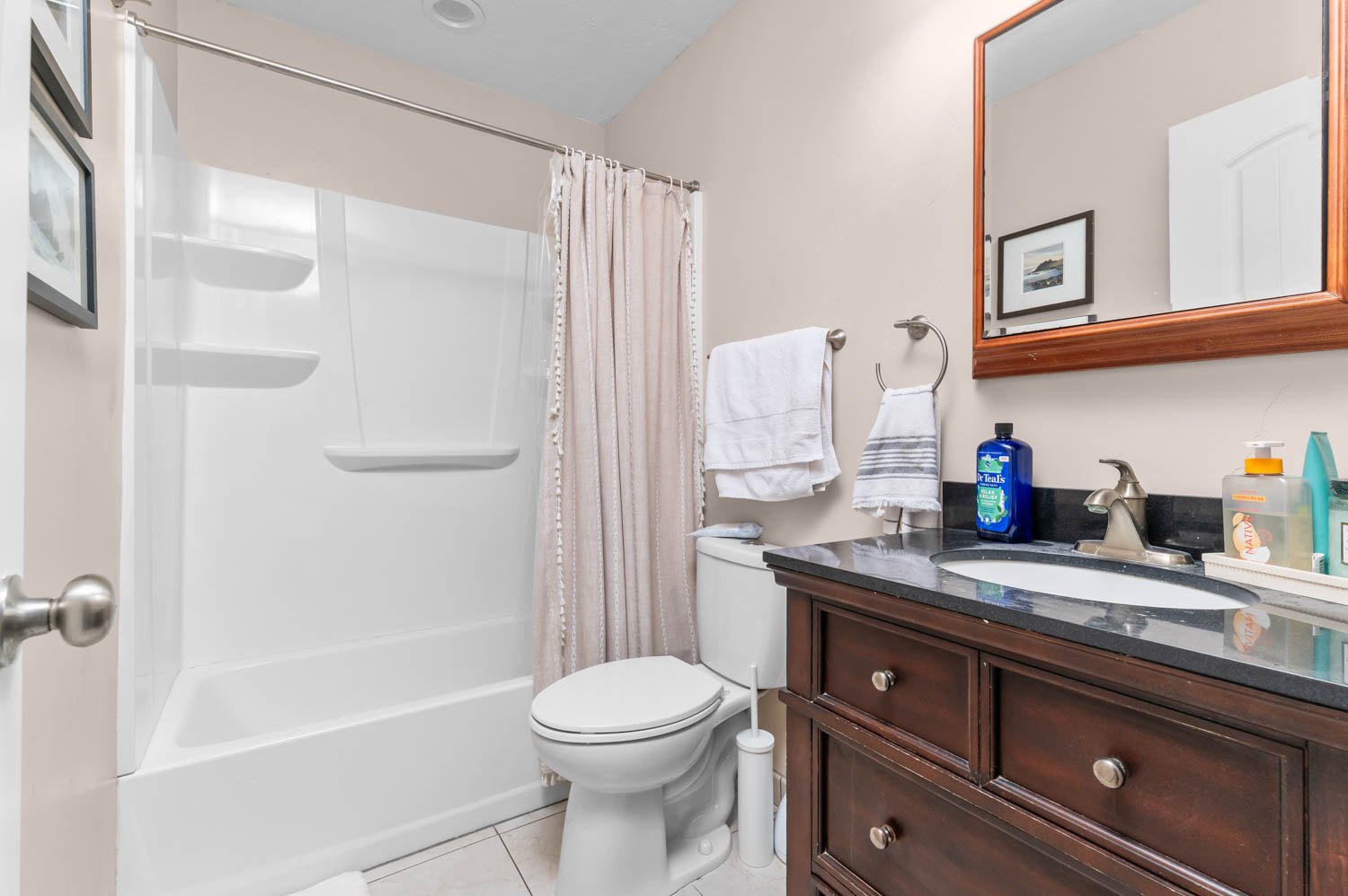 Bathroom featuring a dark wood vanity with a built-in sink, dark countertop, and a wall-mounted mirror