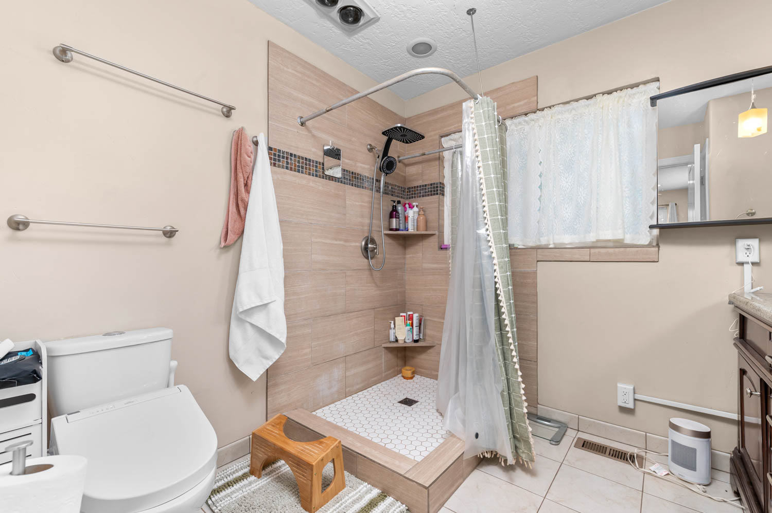 Shower with light-toned rectangular tile surround, hexagonal floor tiles, and built-in shelving
