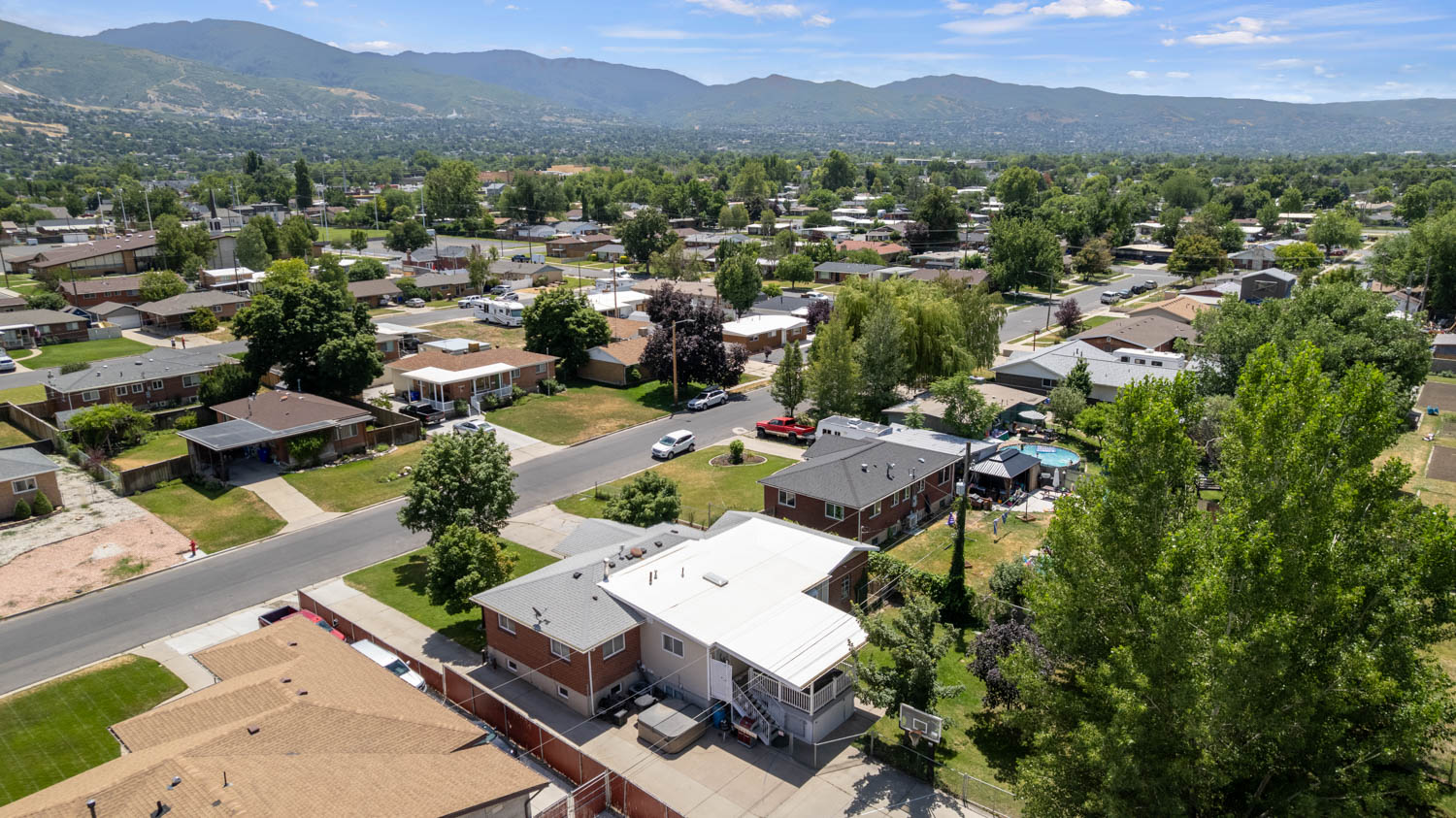 Residential neighborhood with mature trees and mountain backdrop