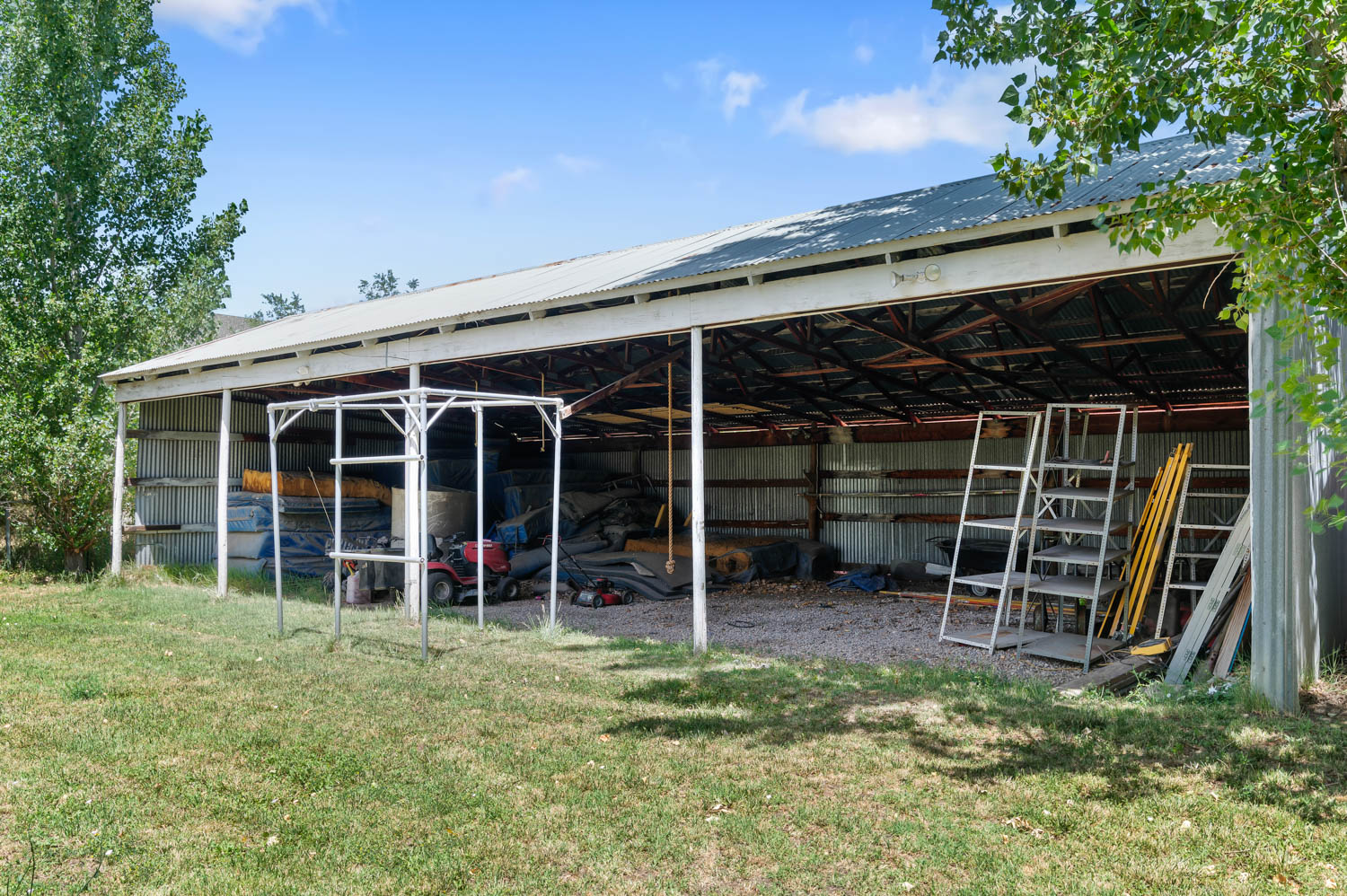 Expansive open-sided barn featuring a metal roof, exposed structural beams, and corrugated metal siding
