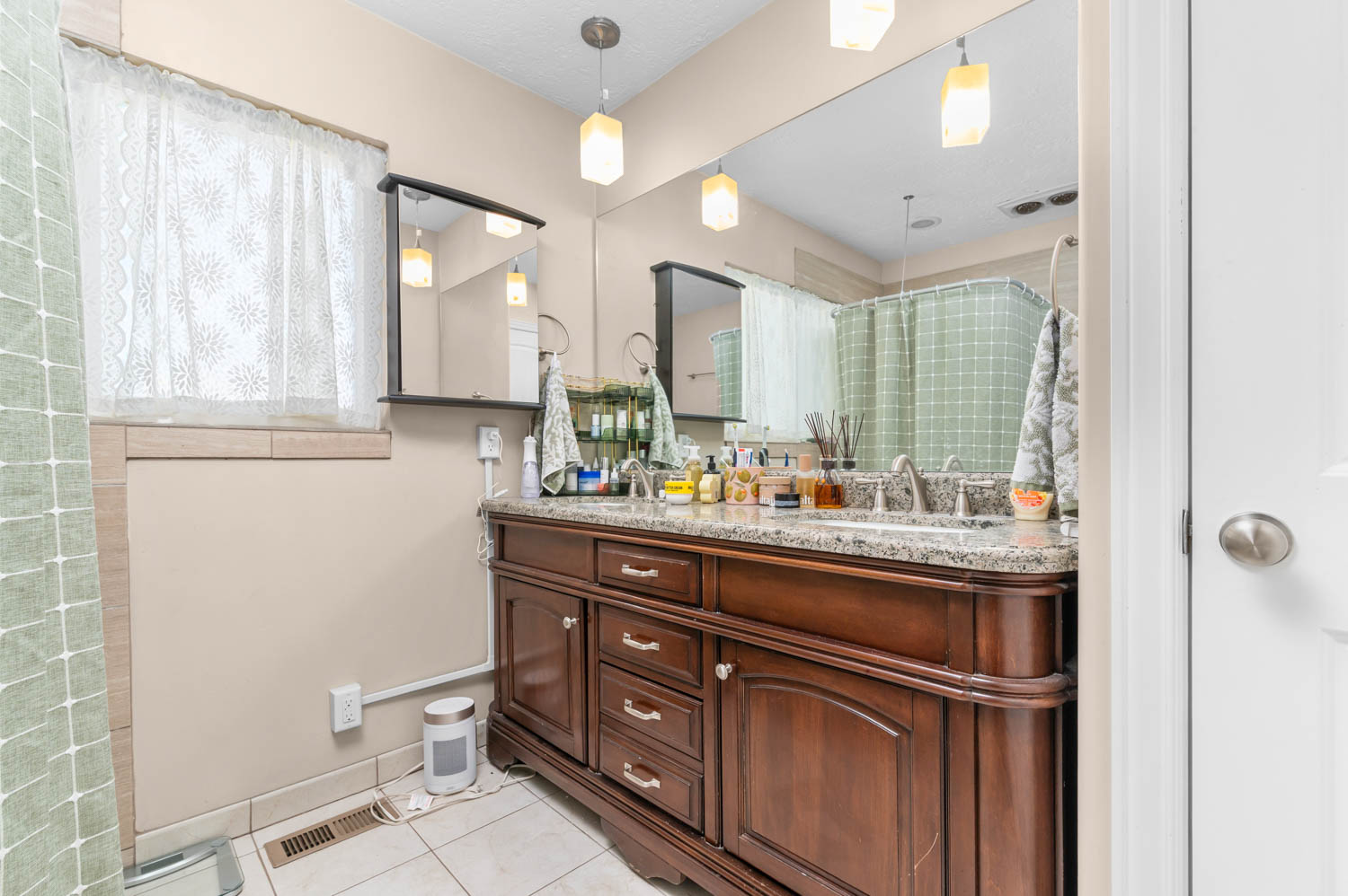 Double vanity with a granite-style countertop, undermount sinks, and a wood-finish cabinet with storage