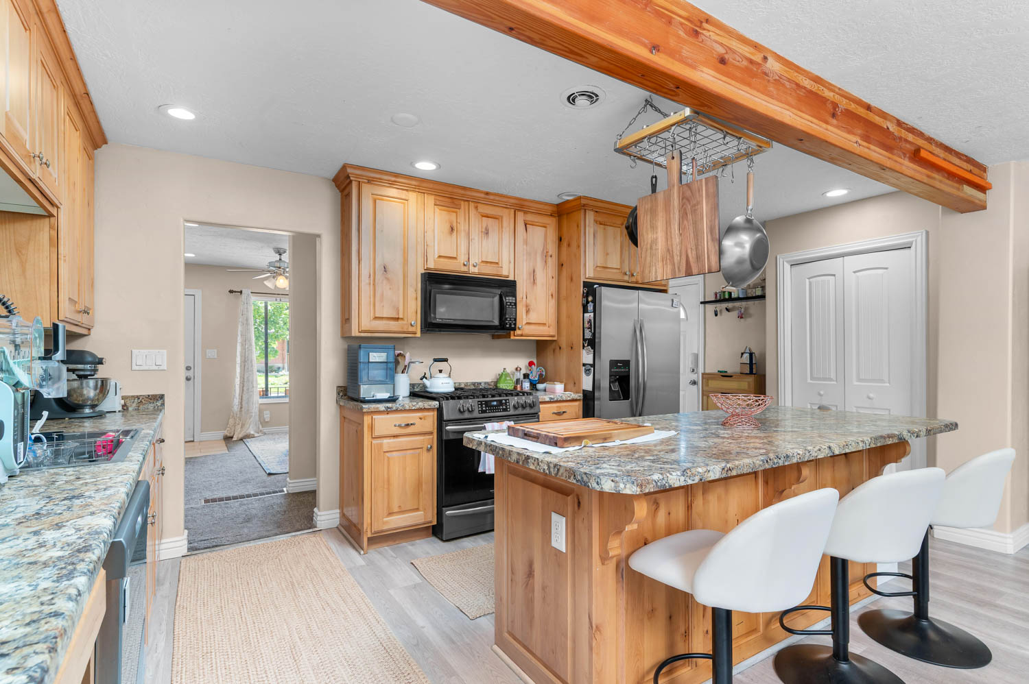 Kitchen featuring warm wood cabinetry, granite countertops, stainless steel refrigerator, black range, and a central island with bar seating