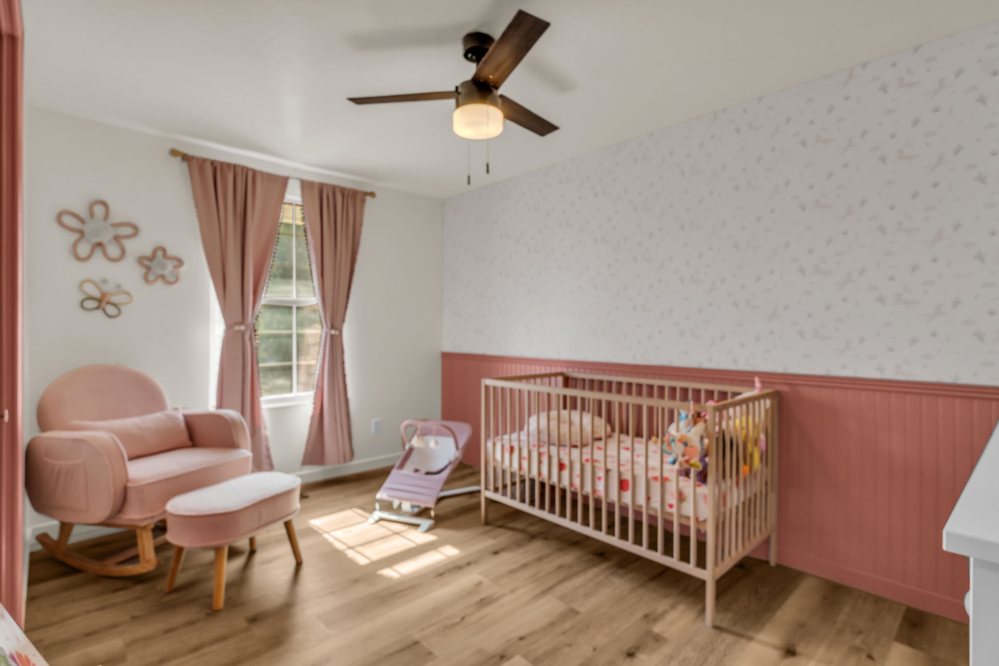 Room featuring wood-finish flooring, a double-hung window, and a ceiling fan with integrated lighting