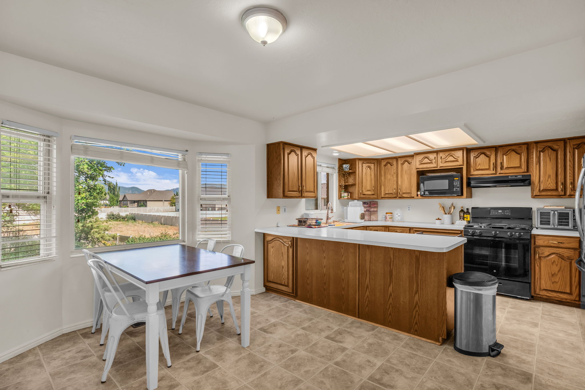 Kitchen featuring wood cabinetry, light countertops, and a full suite of black appliances