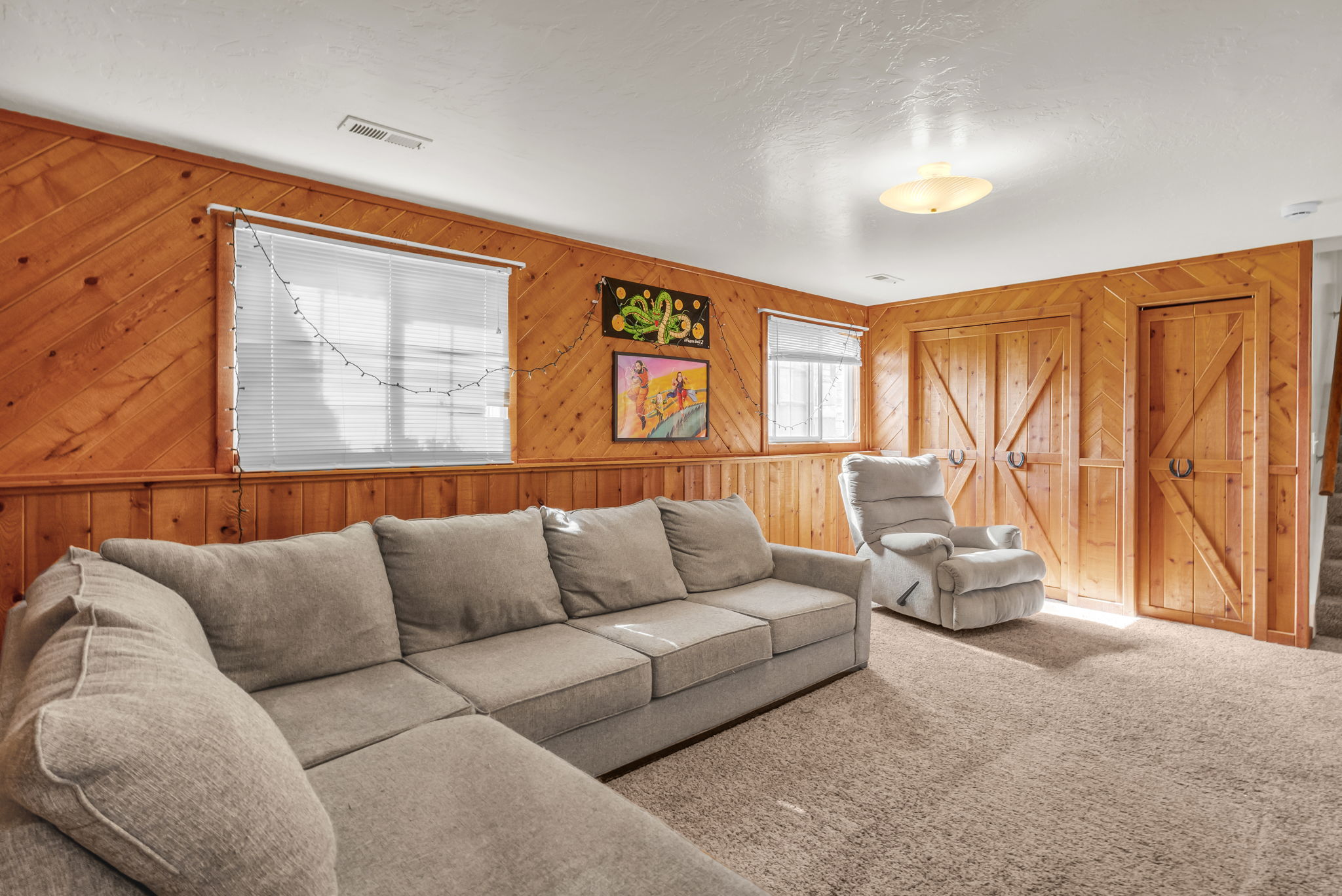 Carpeted room featuring wood paneling, multiple windows with blinds, and built-in barn-style doors