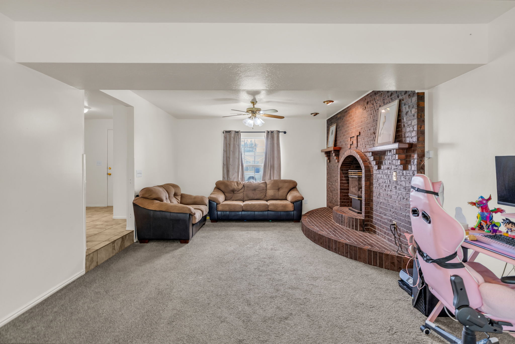 Spacious living area featuring a brick fireplace with a raised hearth, recessed lighting, and a ceiling fan