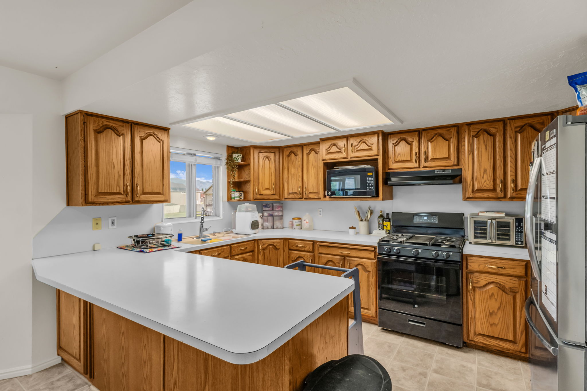 Spacious kitchen featuring extensive wood cabinetry, white countertops, a built-in microwave, and a black gas range