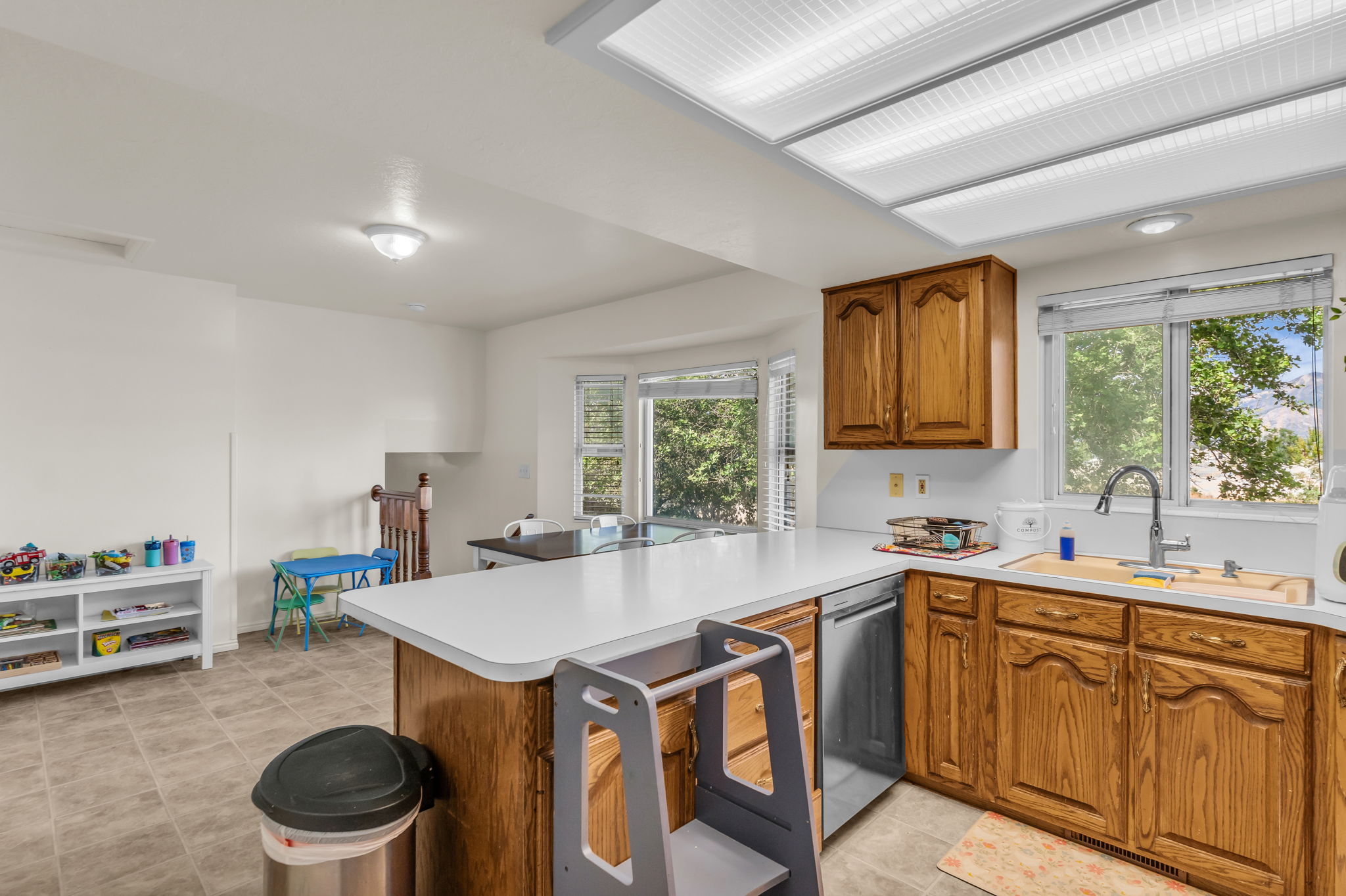Kitchen featuring wood cabinetry, white countertops, stainless steel sink, and tile flooring