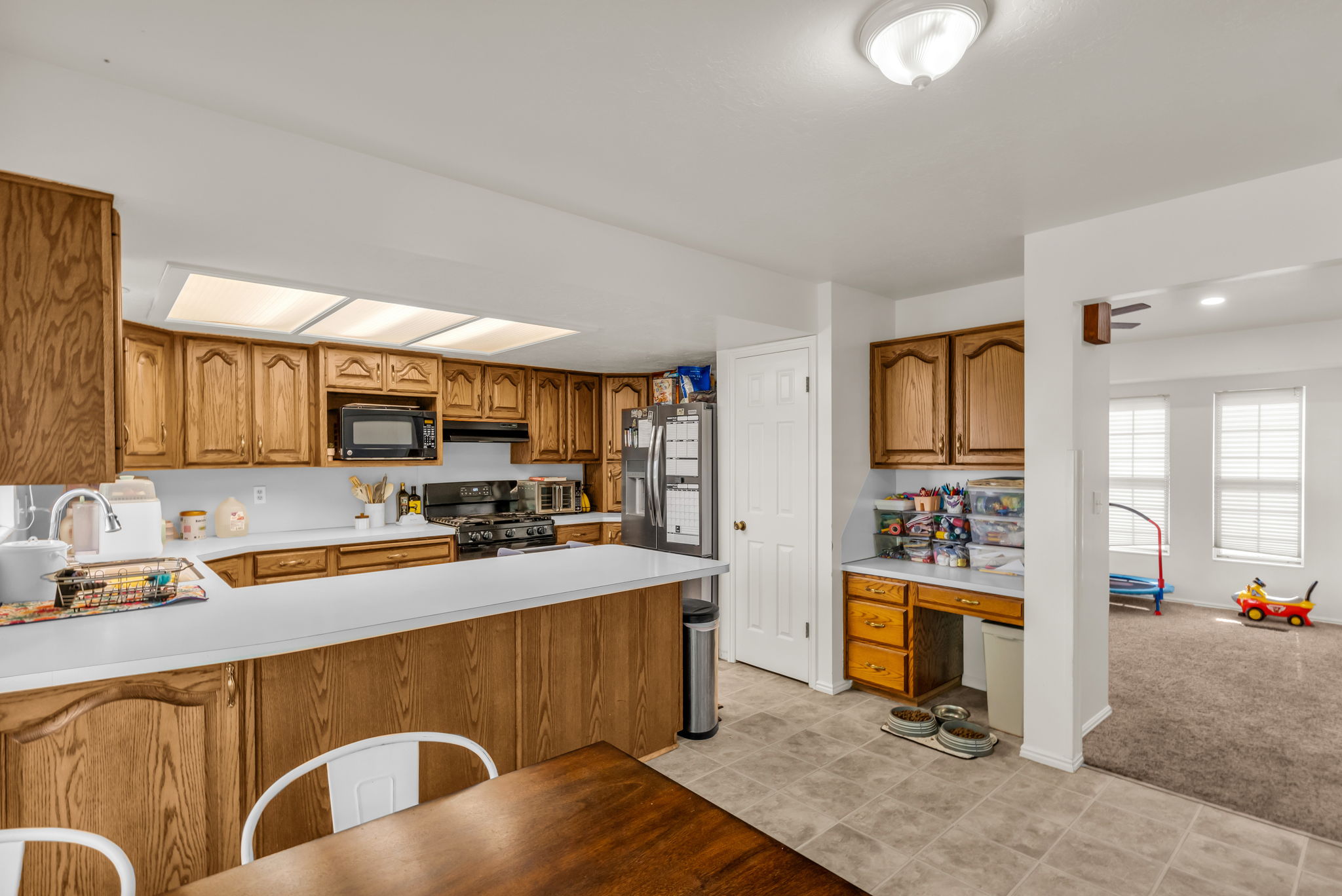 Kitchen featuring wood-finish cabinetry, white countertops, built-in microwave, and a tile floor