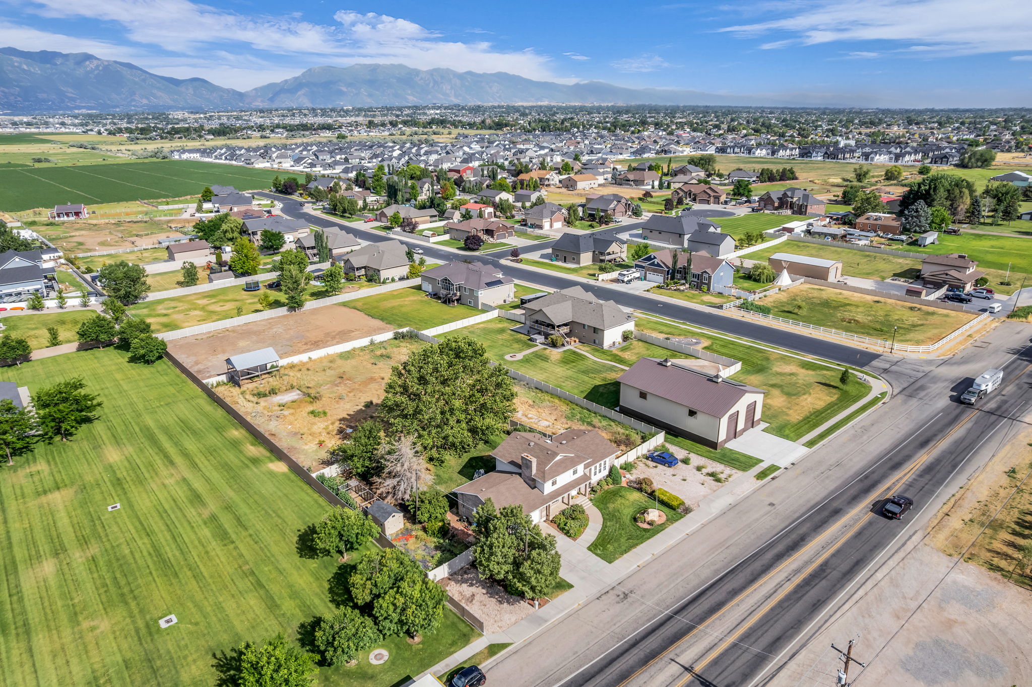 Expansive property featuring a detached garage with double bay doors, a paved driveway, and mature landscaping