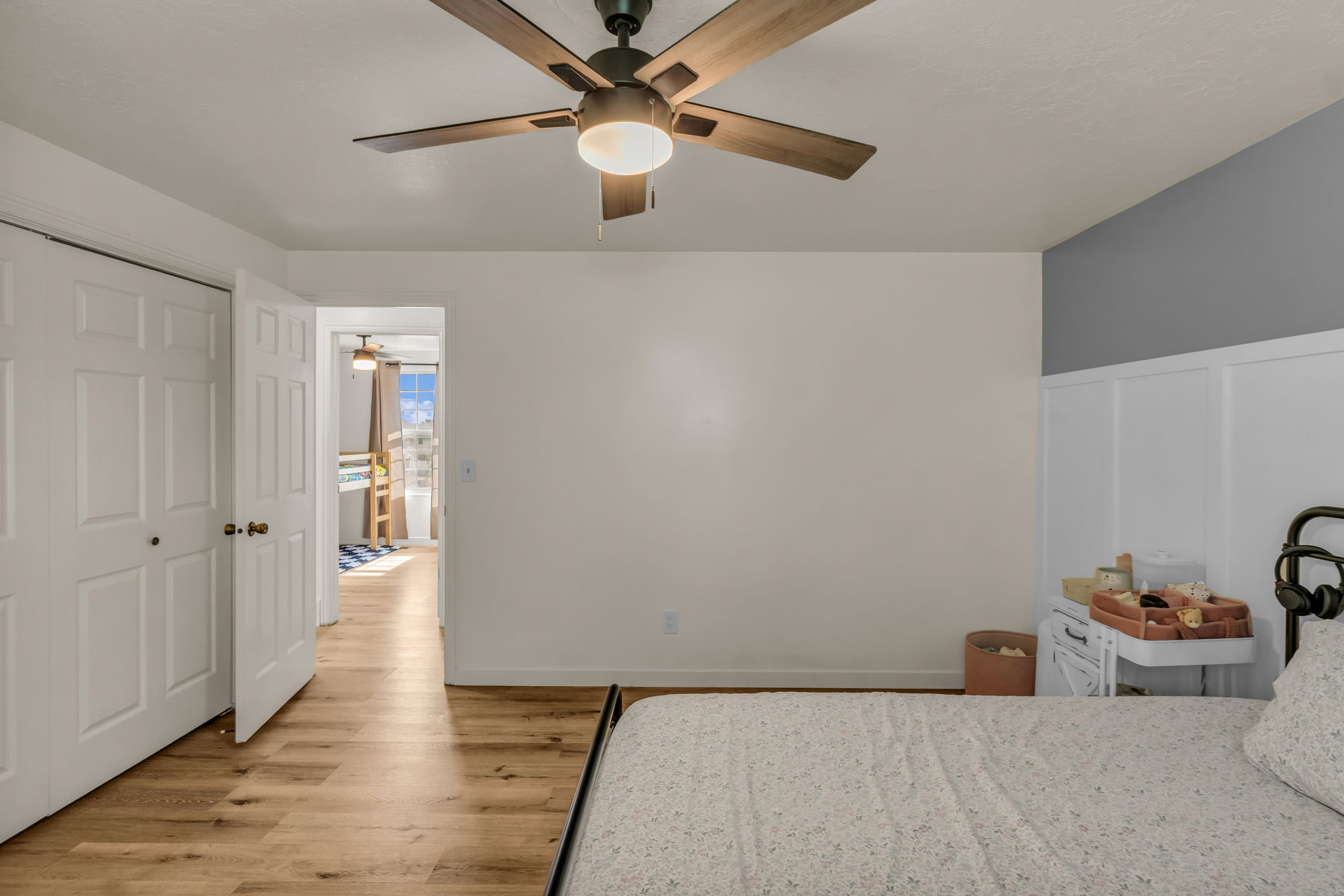 Interior room featuring wood-finish flooring, a ceiling fan with integrated lighting, and a white paneled accent wall
