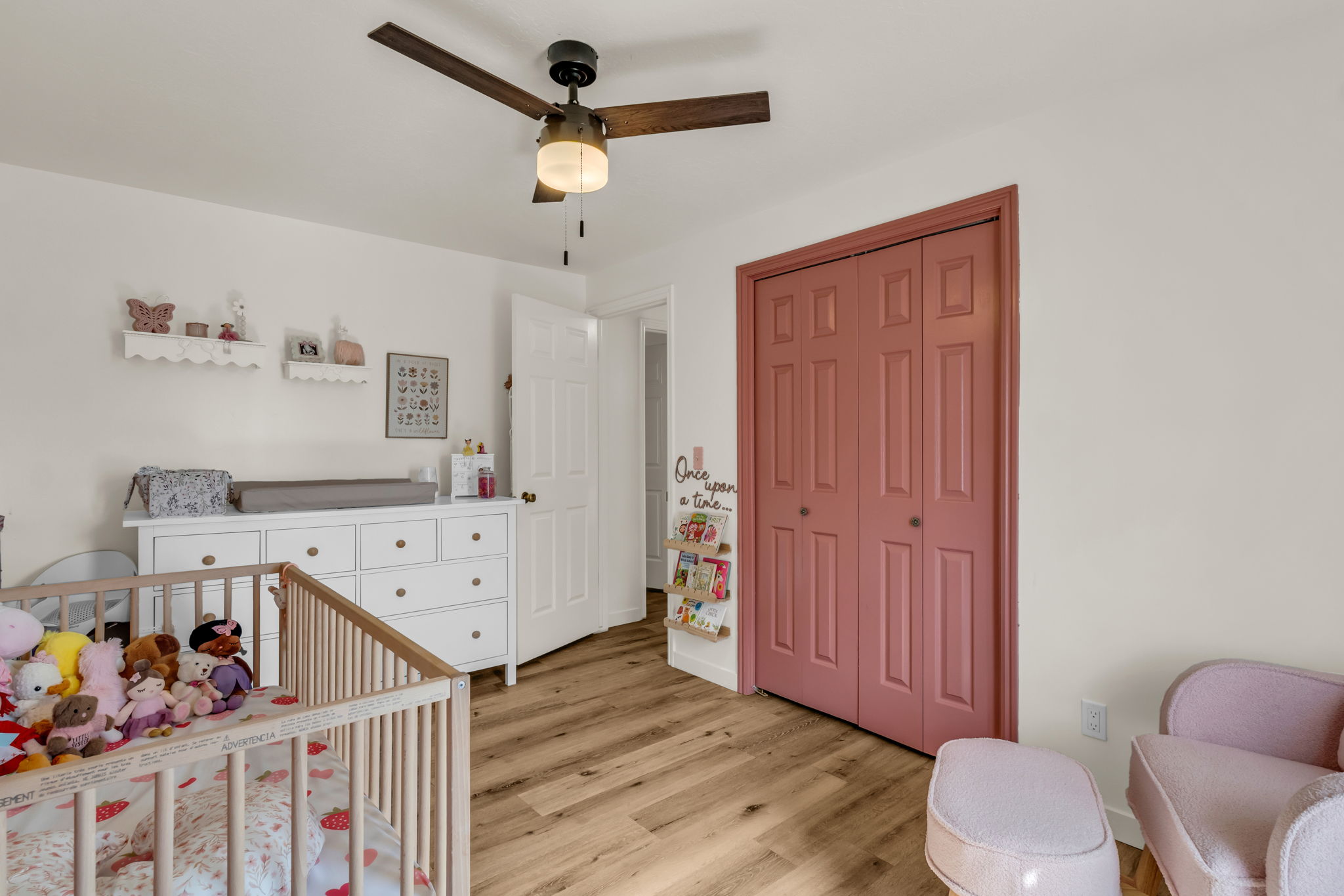 Light wood-finish flooring provides a warm foundation for this room, featuring a dark wood-finish ceiling fan with integrated lighting