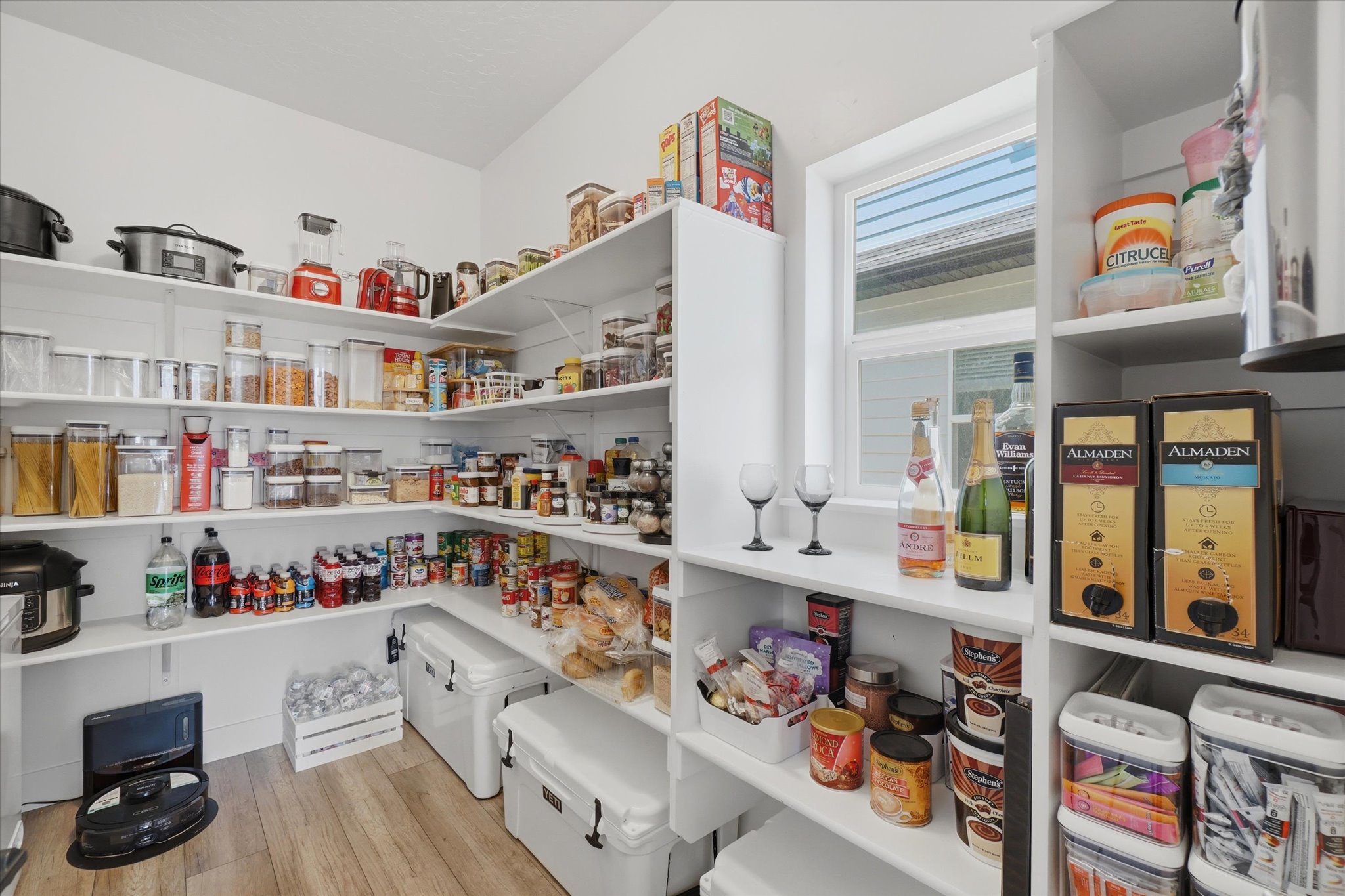 Walk-in pantry featuring extensive shelving, wood-finish flooring, and a natural light window