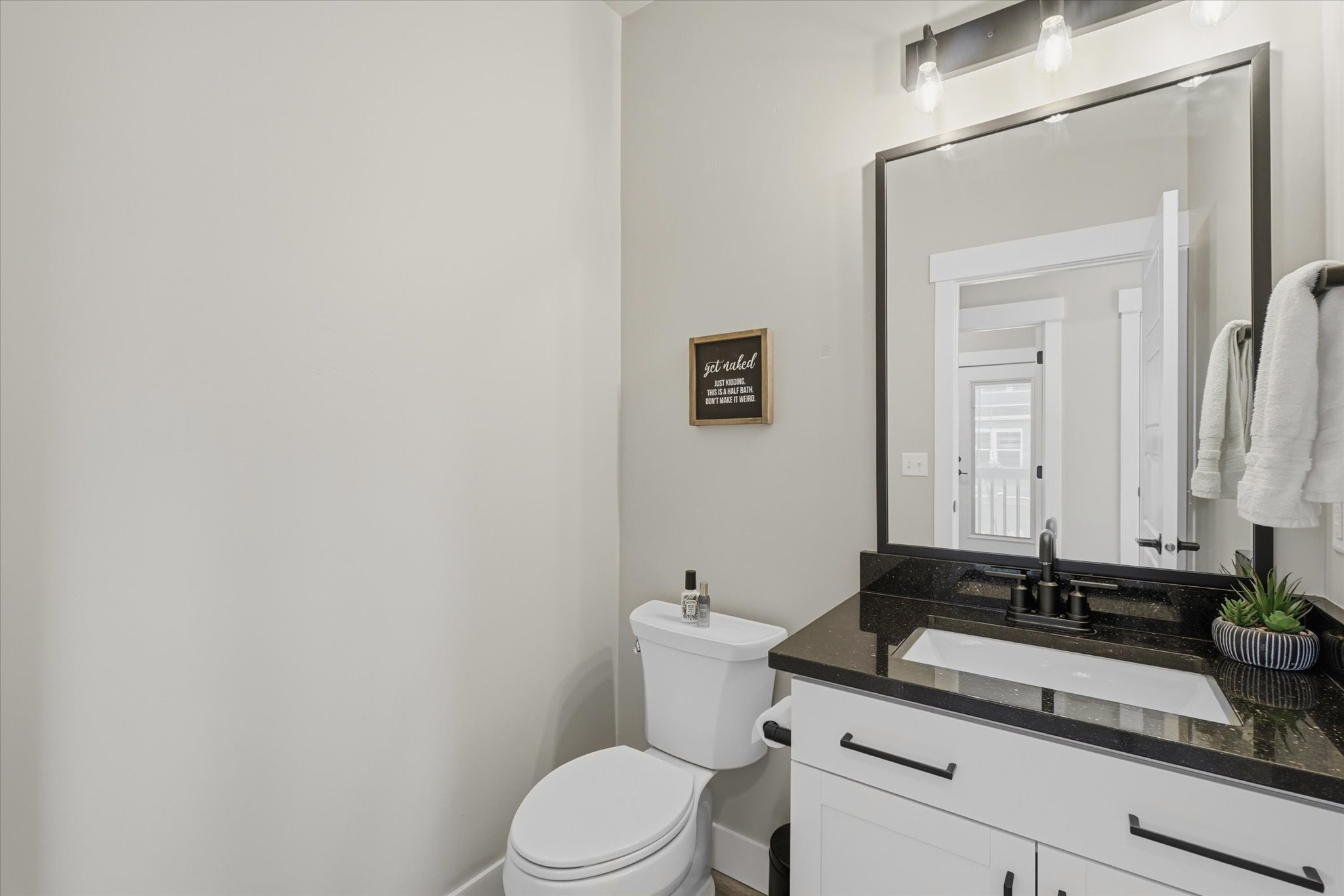 White vanity with black hardware, black countertop, and rectangular undermount sink