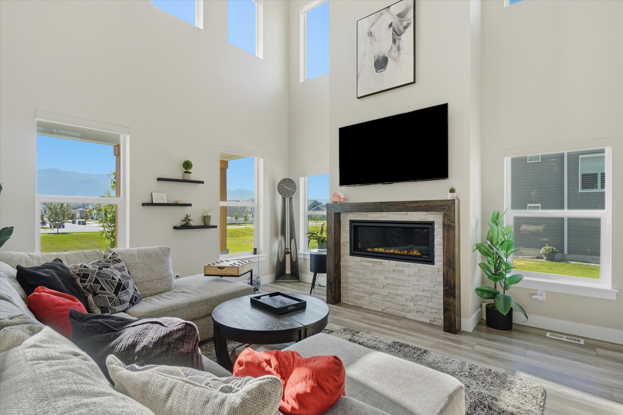 Two-story living area featuring a built-in linear fireplace with a stacked stone facade and wood-finish surround