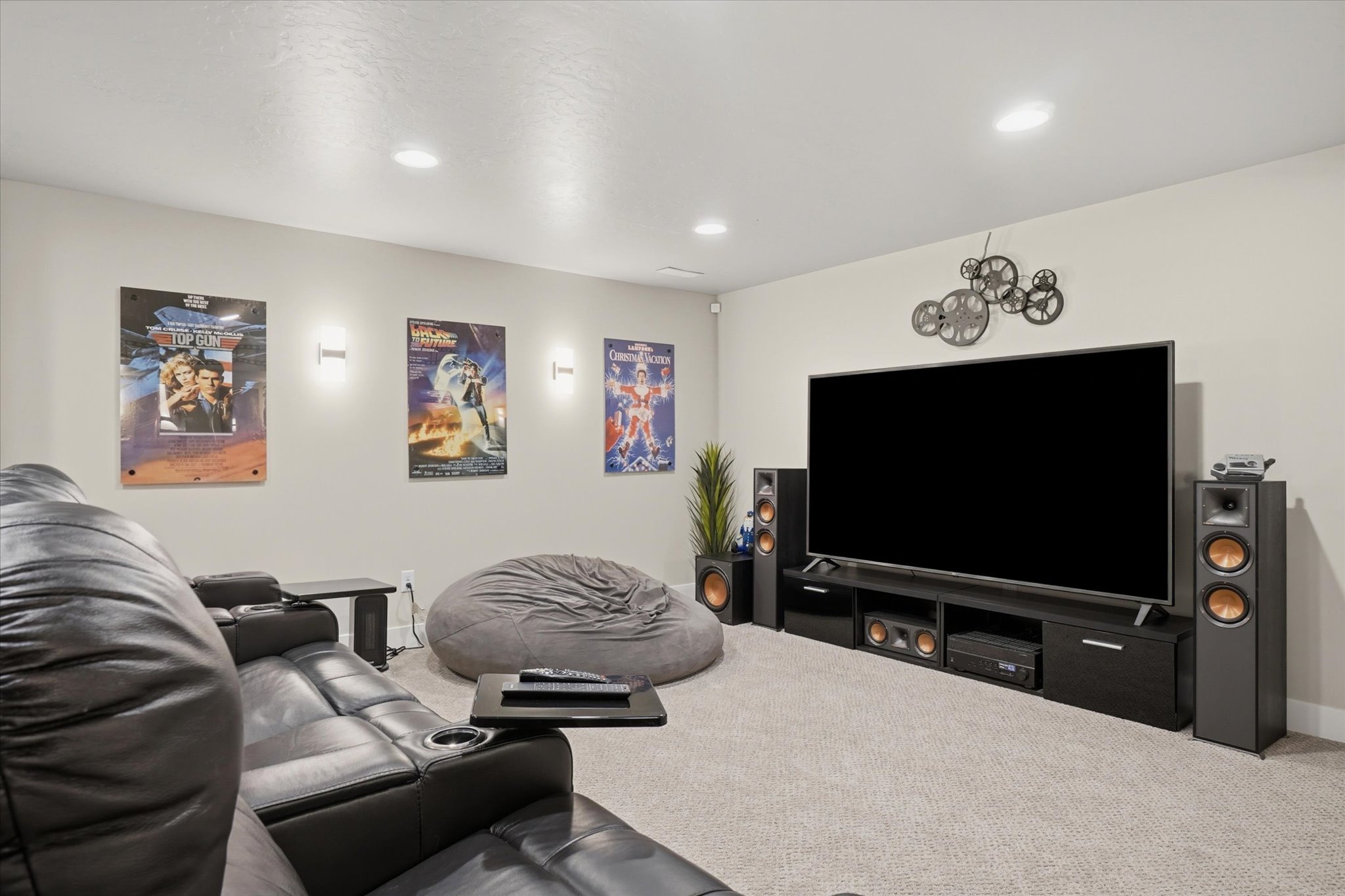 Spacious entertainment area featuring recessed lighting, wall sconces, and neutral carpeting