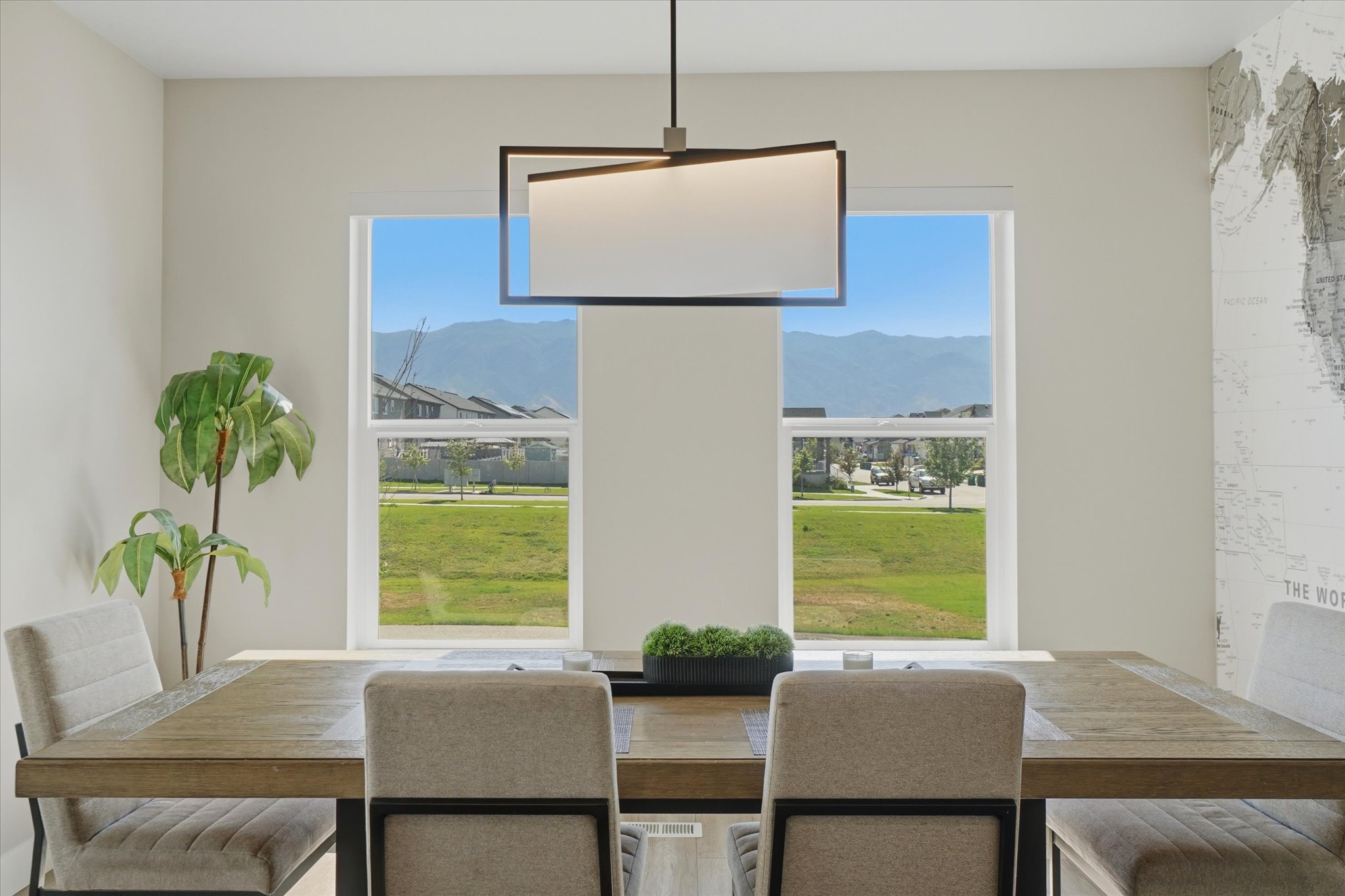 Dining area featuring a modern rectangular chandelier, two large windows, and an accent wall with a world map graphic
