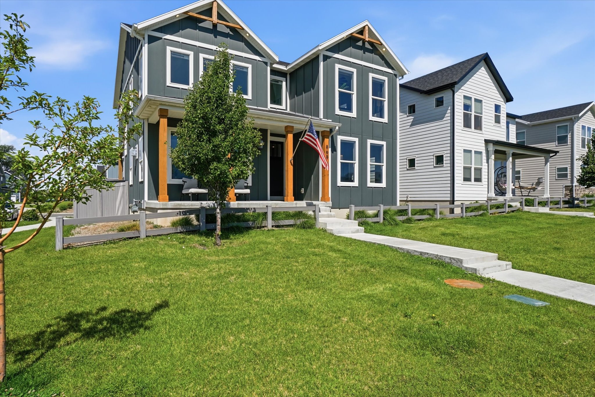 Modern two-story home featuring dark gray vertical siding with white trim accents