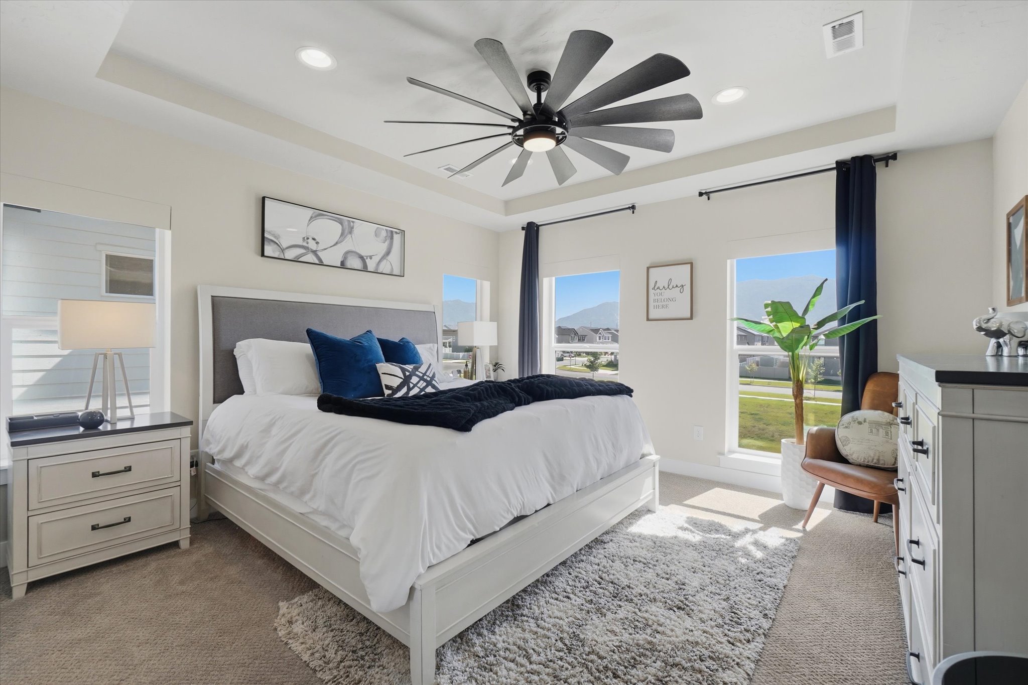 Spacious bedroom featuring a tray ceiling with recessed lighting and a contemporary ceiling fan