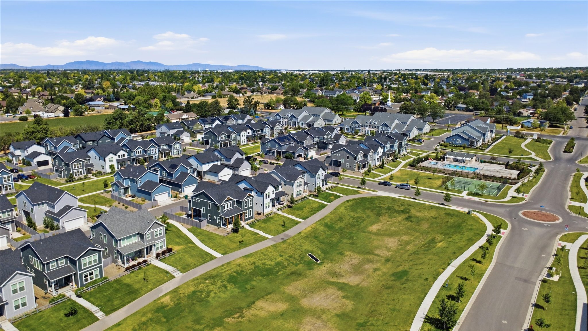 Newly developed residential community featuring a variety of home styles, expansive green spaces, and paved walking paths