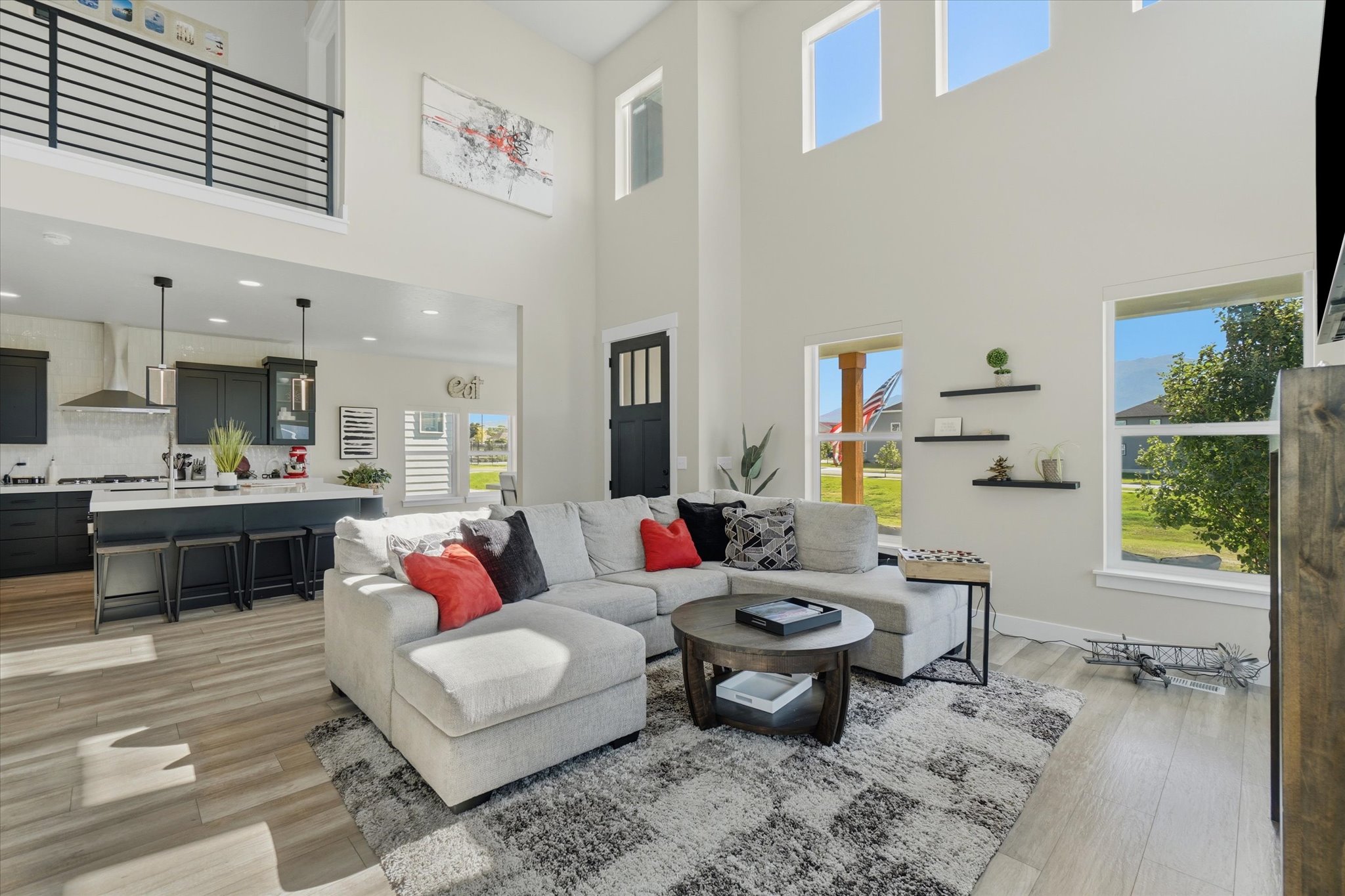 Spacious living area with high ceilings, wood-finish flooring, and ample natural light from multiple windows