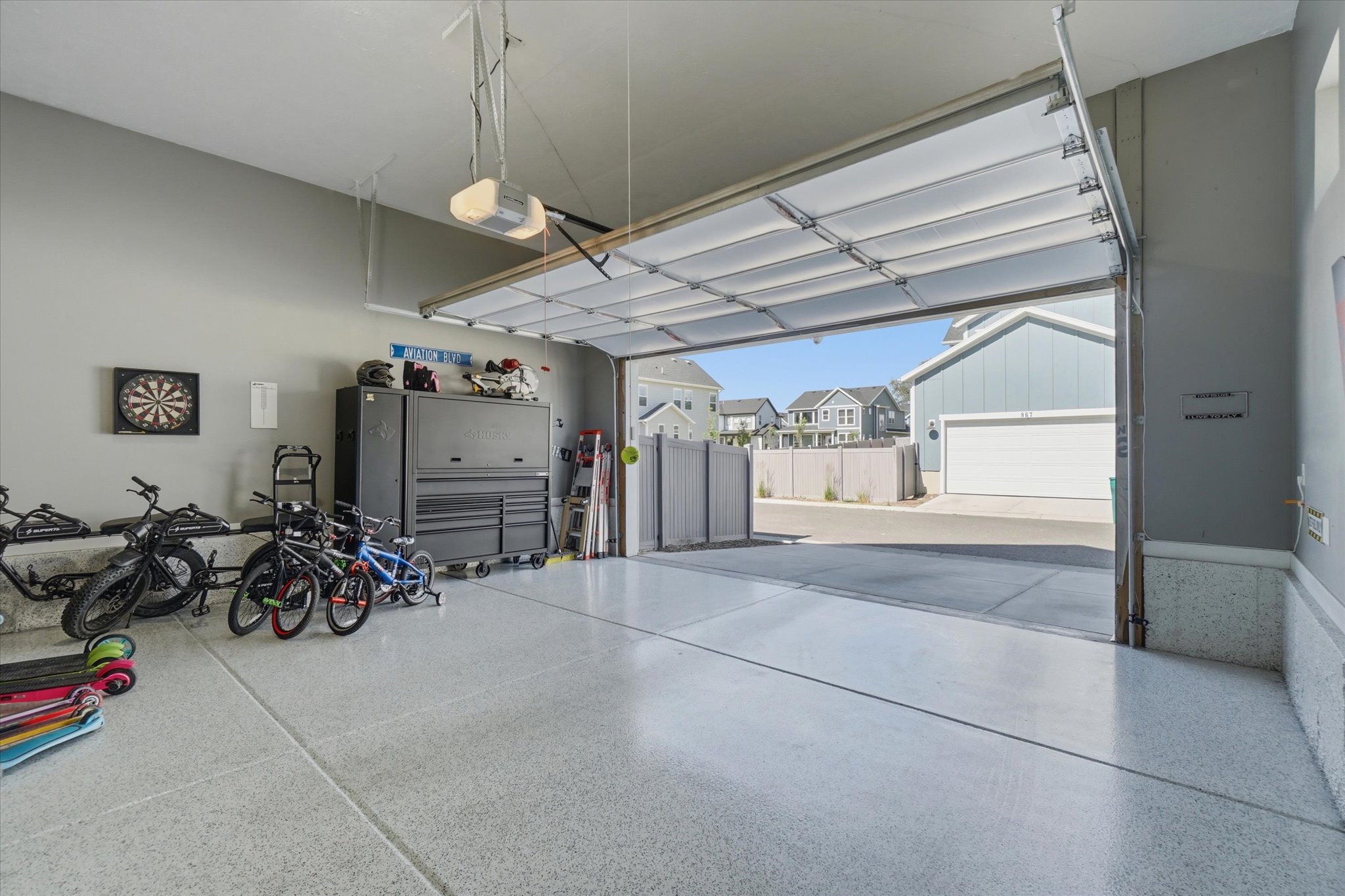 Spacious garage featuring a light gray epoxy floor coating, painted walls, and an automatic overhead door