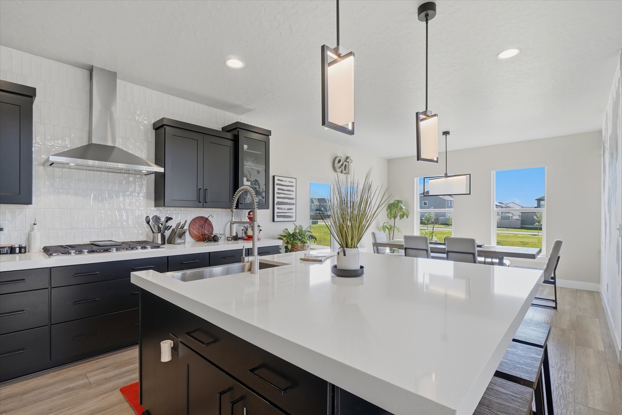 Gourmet kitchen featuring a large island with a solid surface countertop, matte black cabinetry, stainless steel appliances, a white subway tile backsplash, and recessed lighting