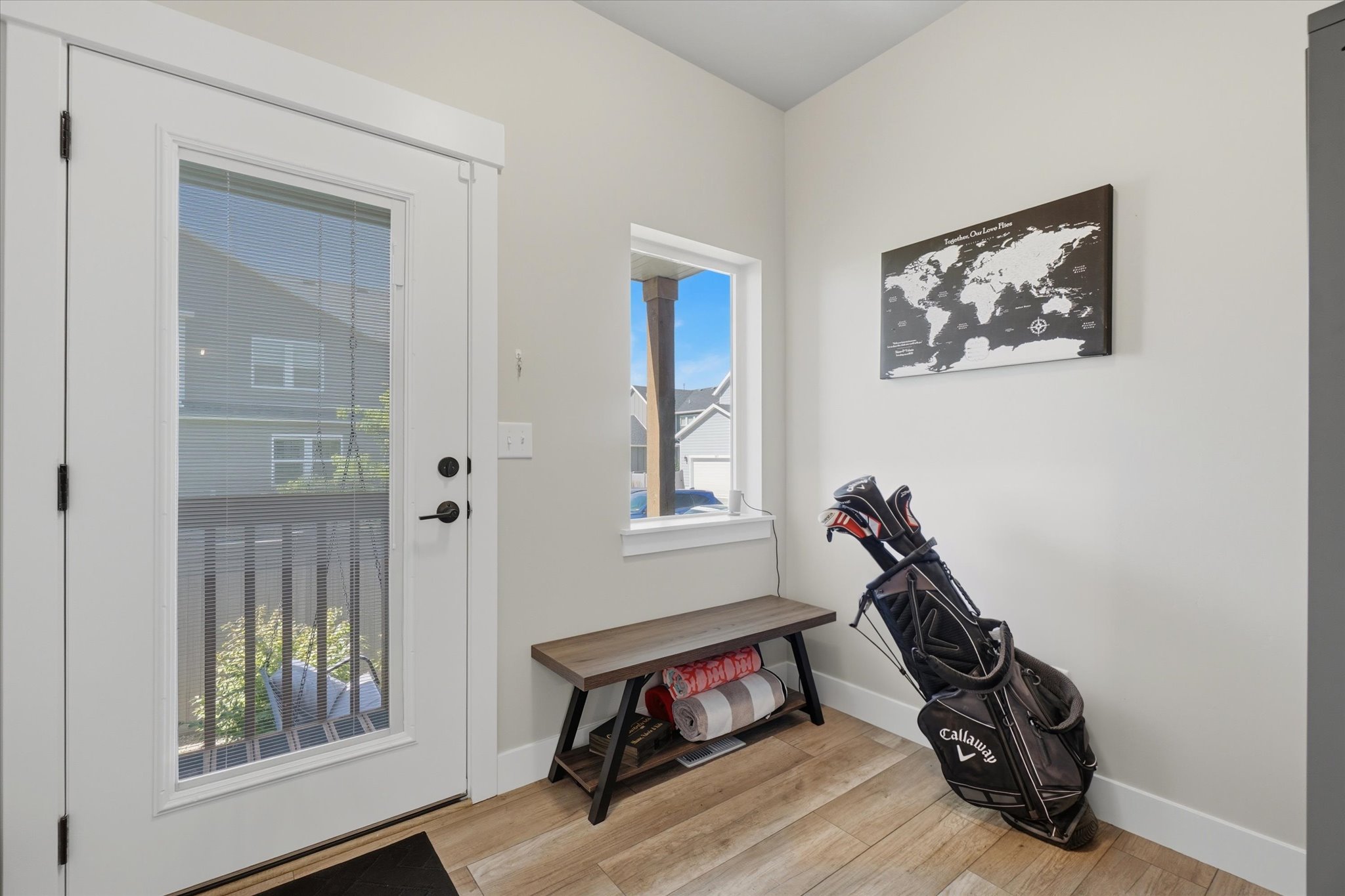 Entryway featuring wood-finish flooring, a full-lite exterior door with integrated blinds, and a large single-hung window with white trim