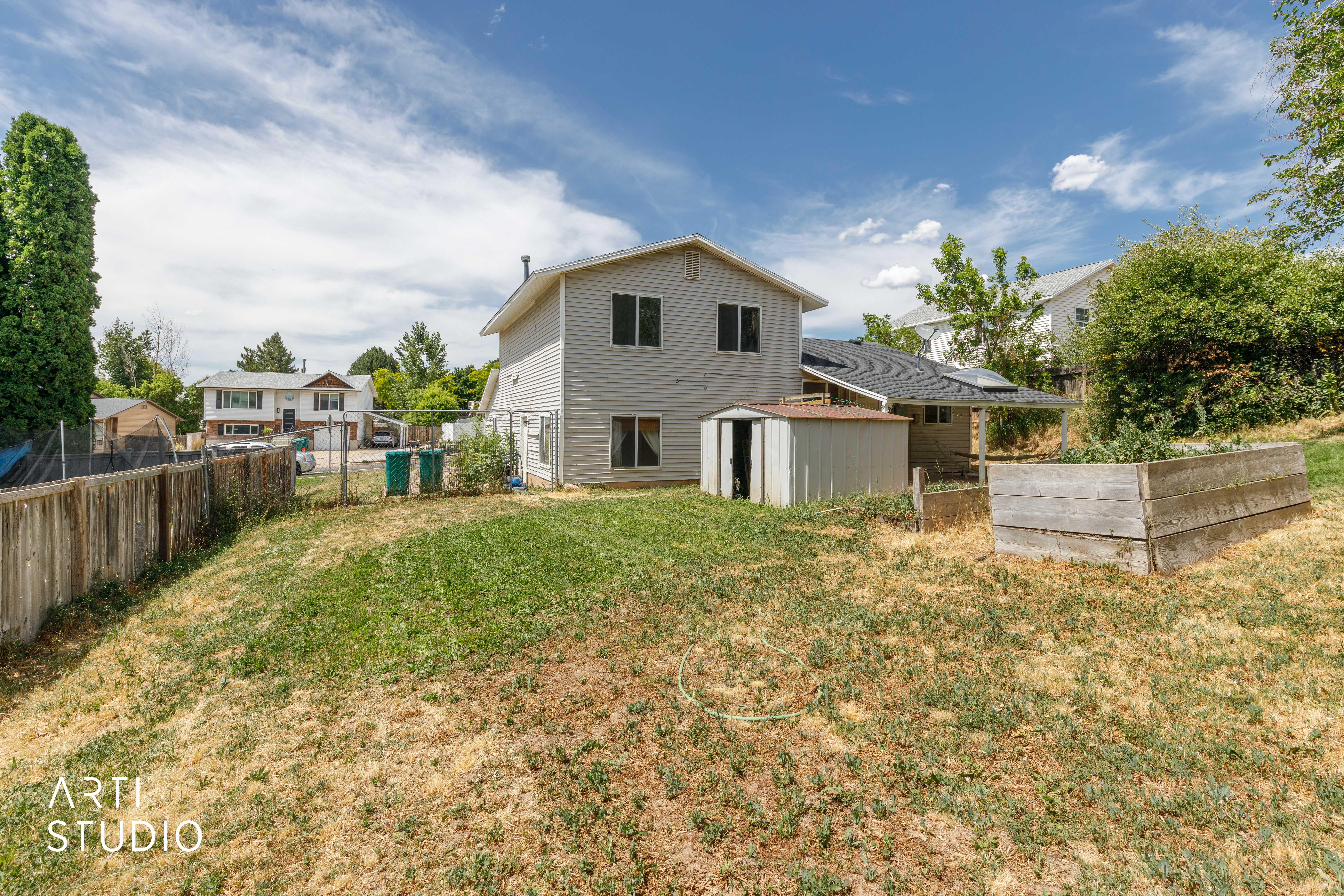 Expansive backyard featuring a wood fence, a detached shed, and a raised garden bed
