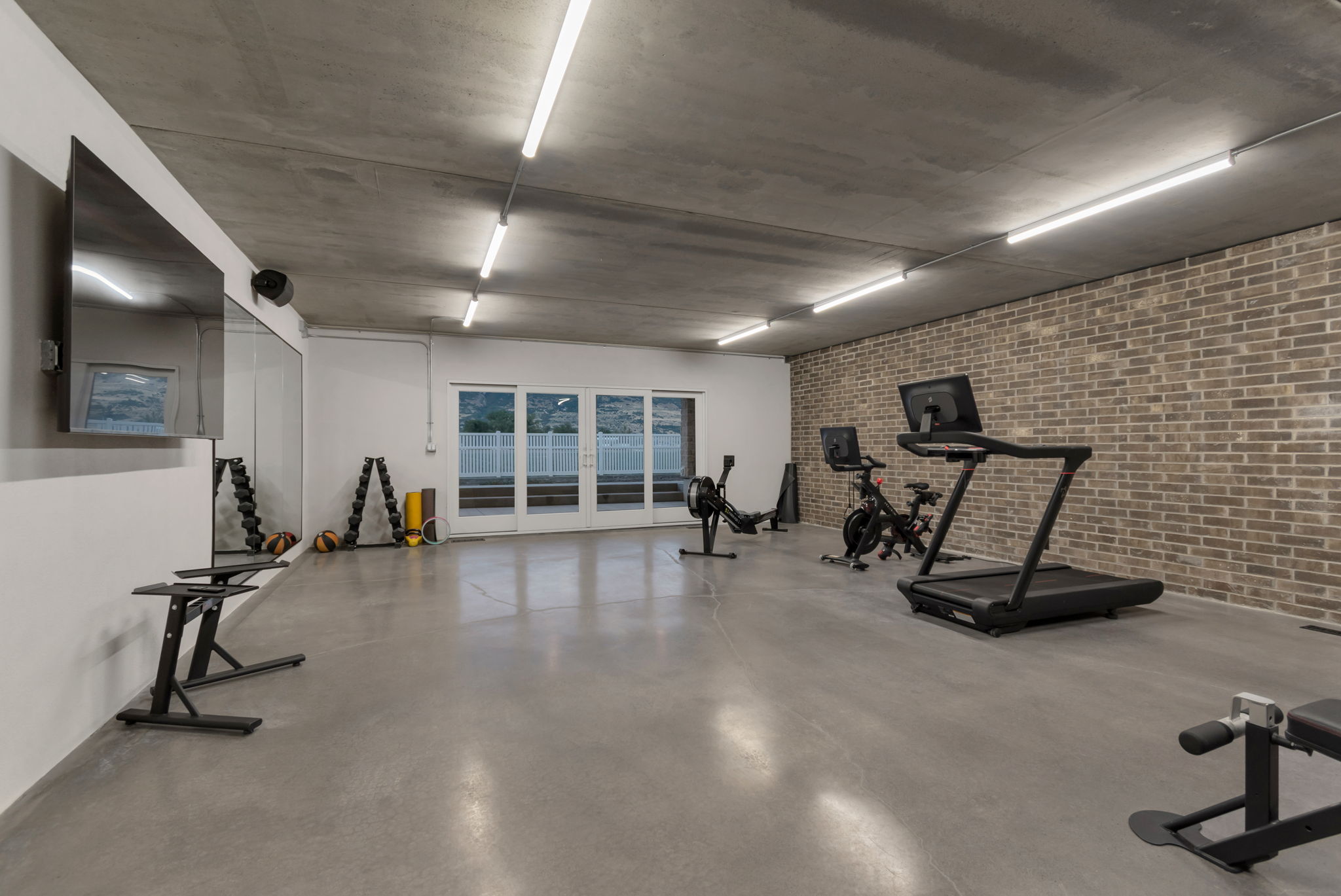Gigantic home gym, with brick accent wall and sliding doors to the backyard