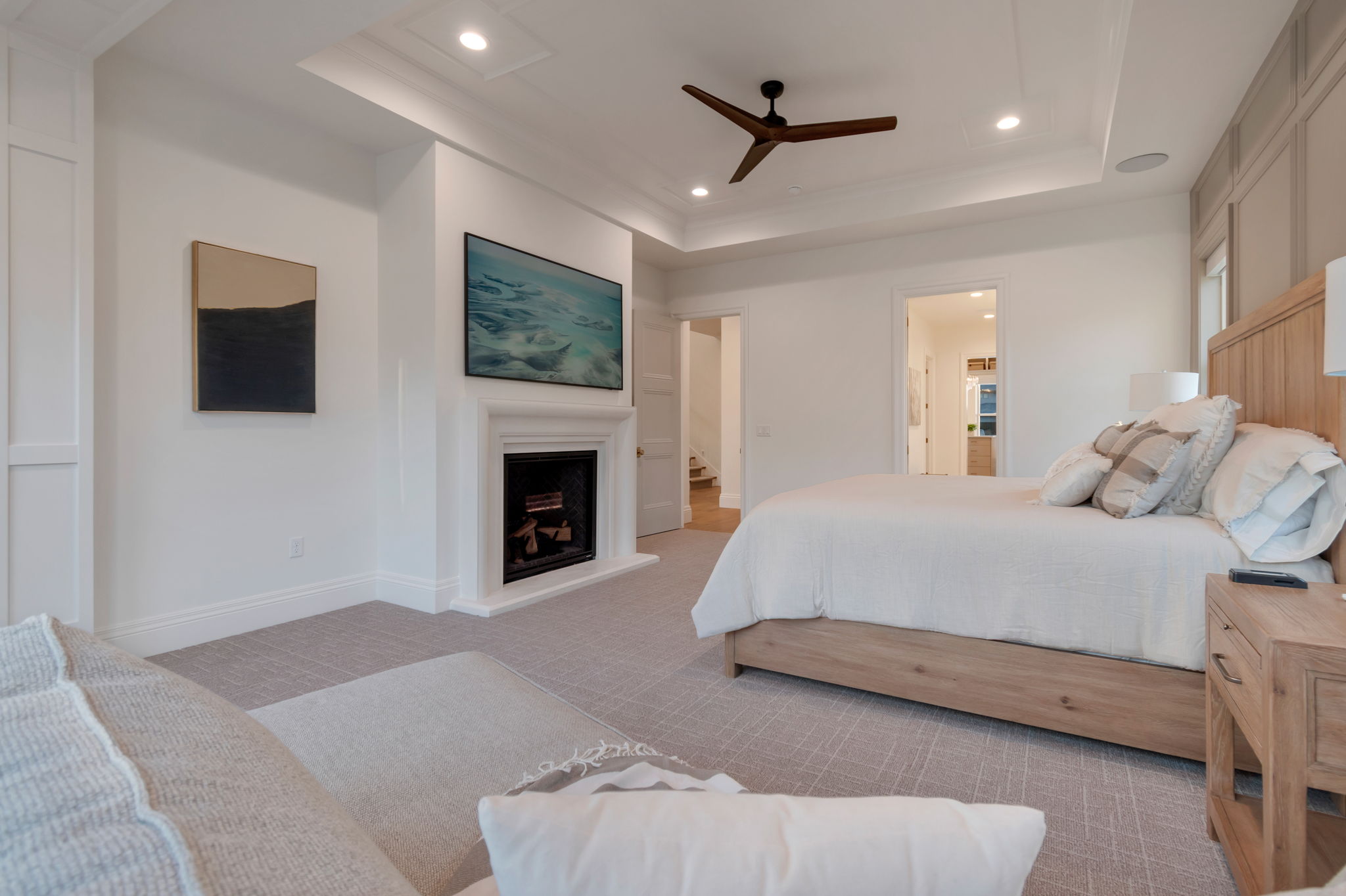 Recessed fireplace with hearth, wood-finish ceiling fan, tray ceiling, recessed lighting, and wall paneling