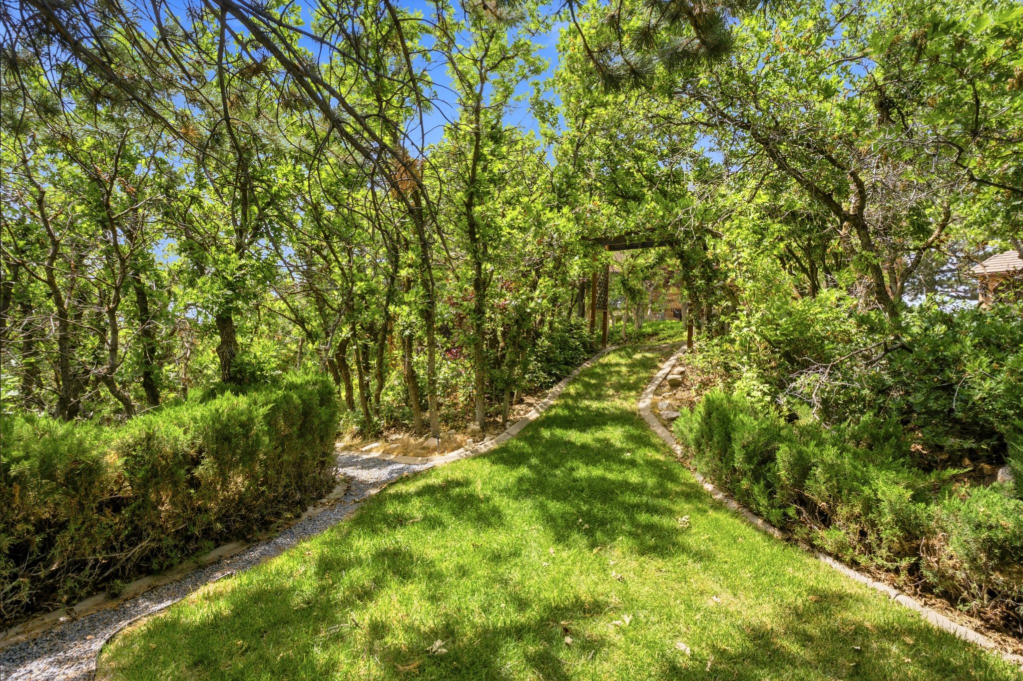 Landscaped grounds featuring pathways, manicured lawn, abundant mature trees, and established shrubbery