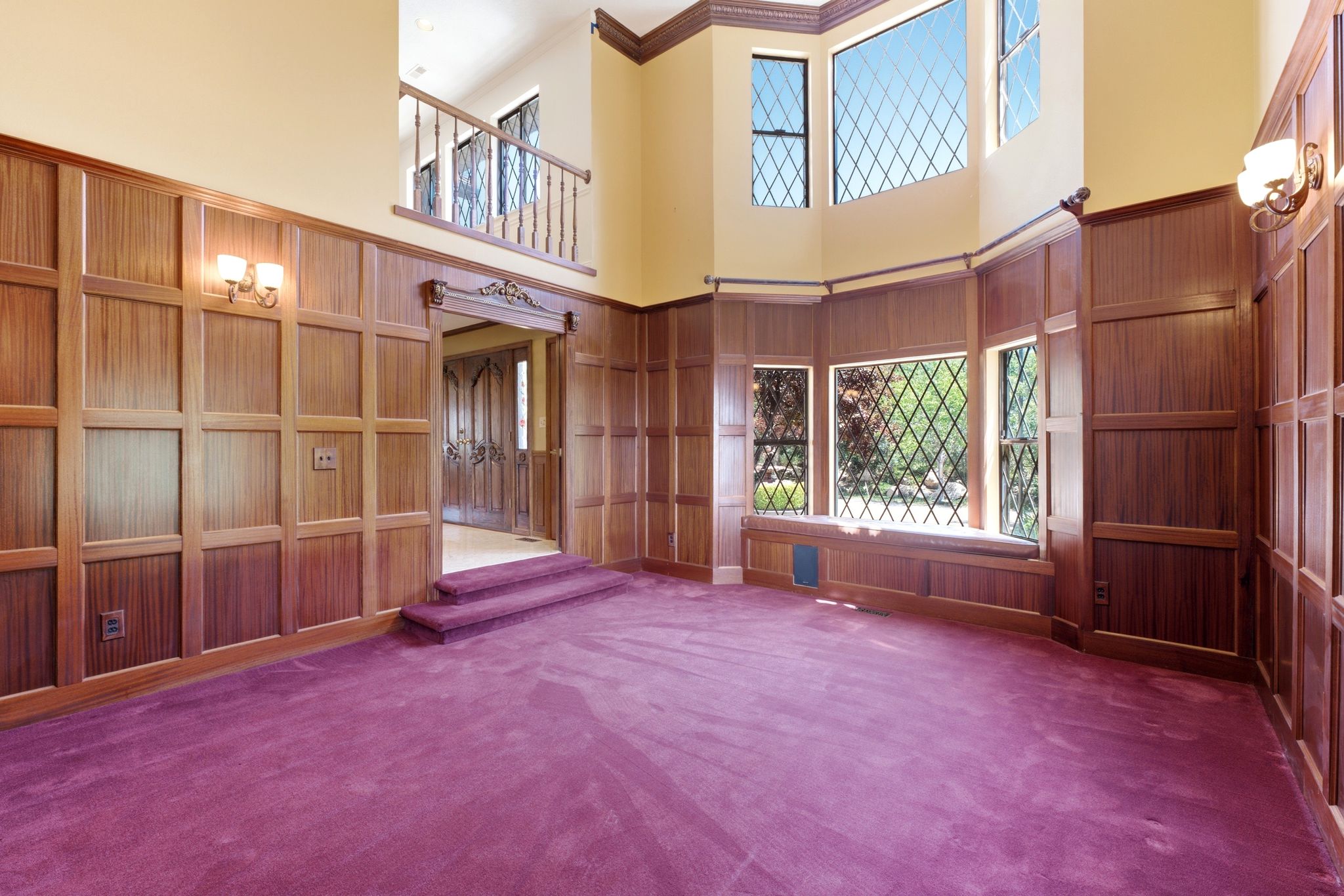Room featuring extensive wood paneling, a multi-pane bay window with diamond-pattern grilles, and a window seat
