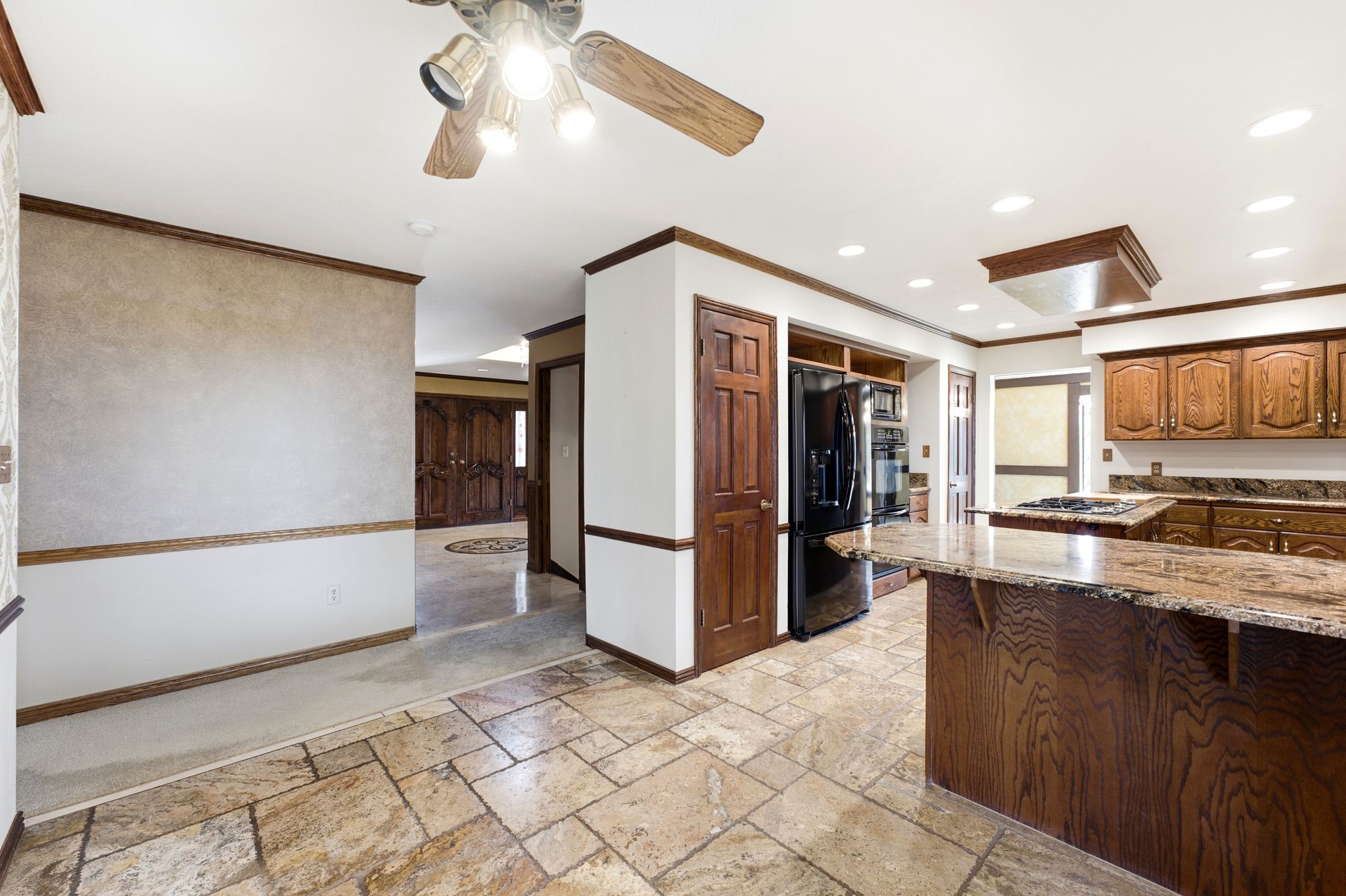 Kitchen featuring stone tile flooring, wood cabinetry, stone countertops, and recessed lighting