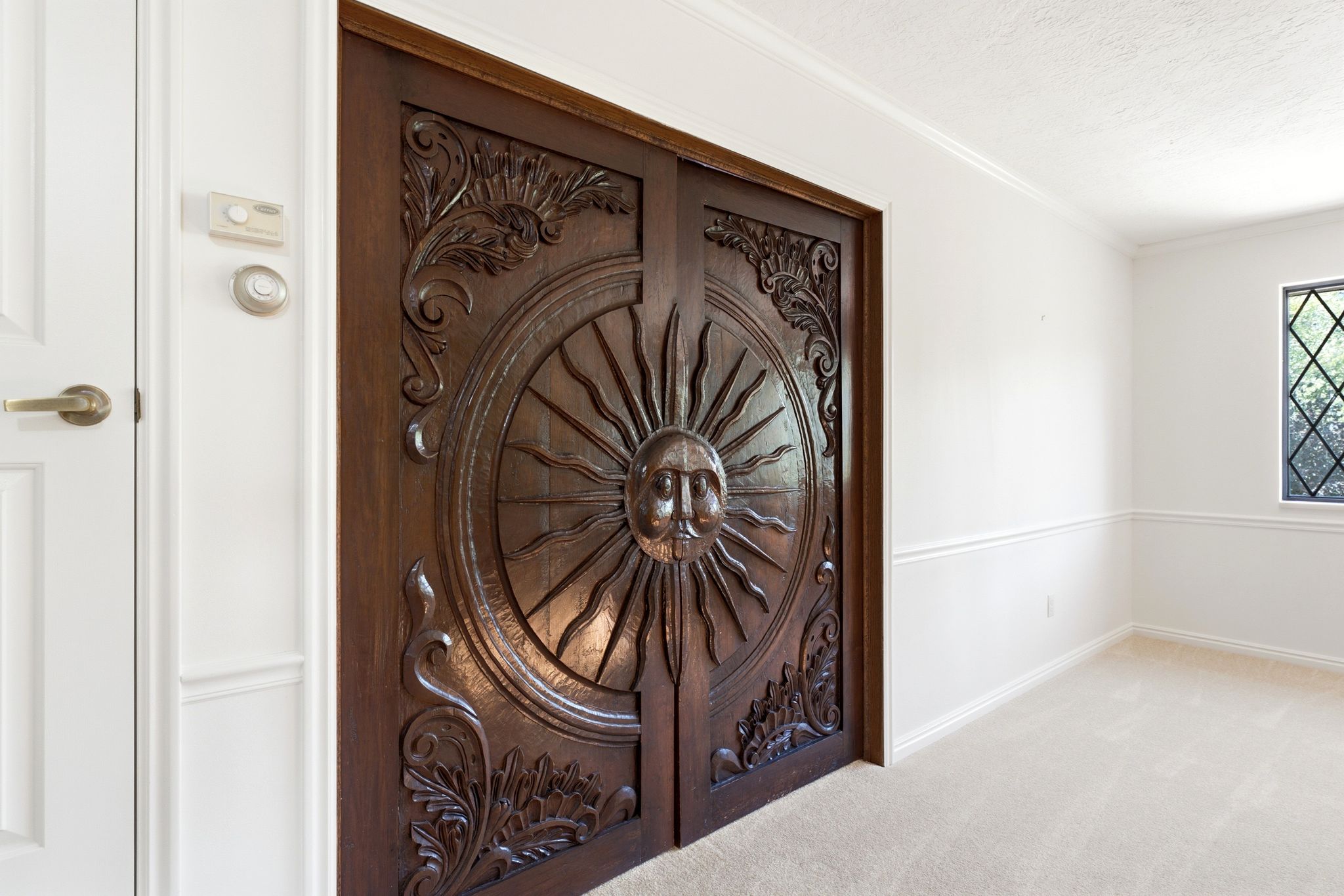 Intricately carved custom double doors lead to primary suite