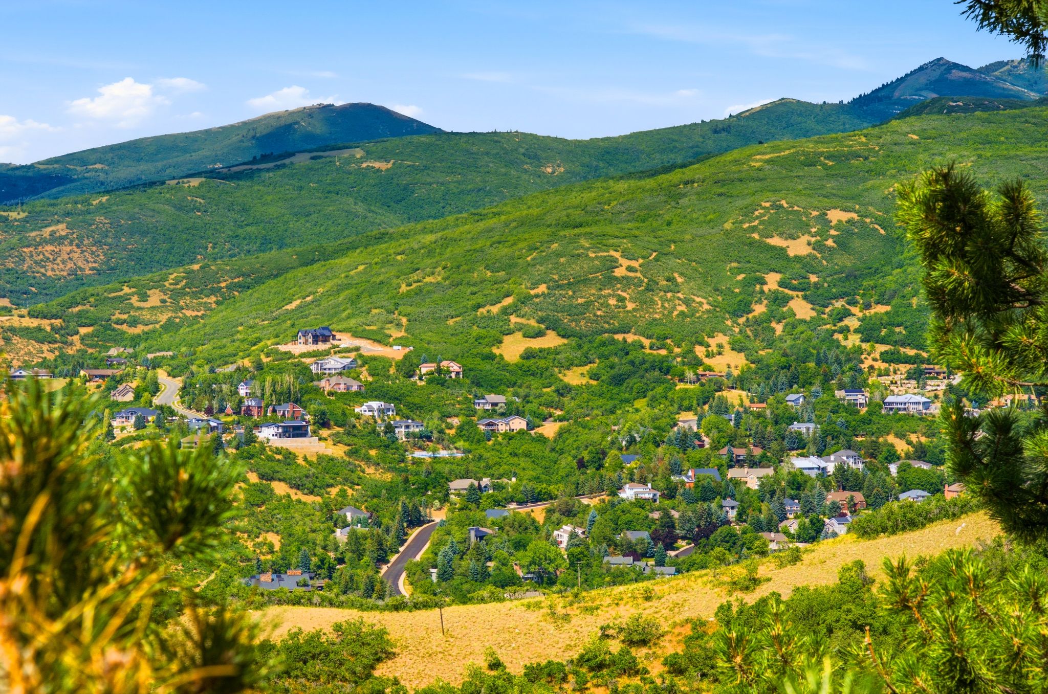 Expansive mountain landscape with a residential community nestled within lush green hills