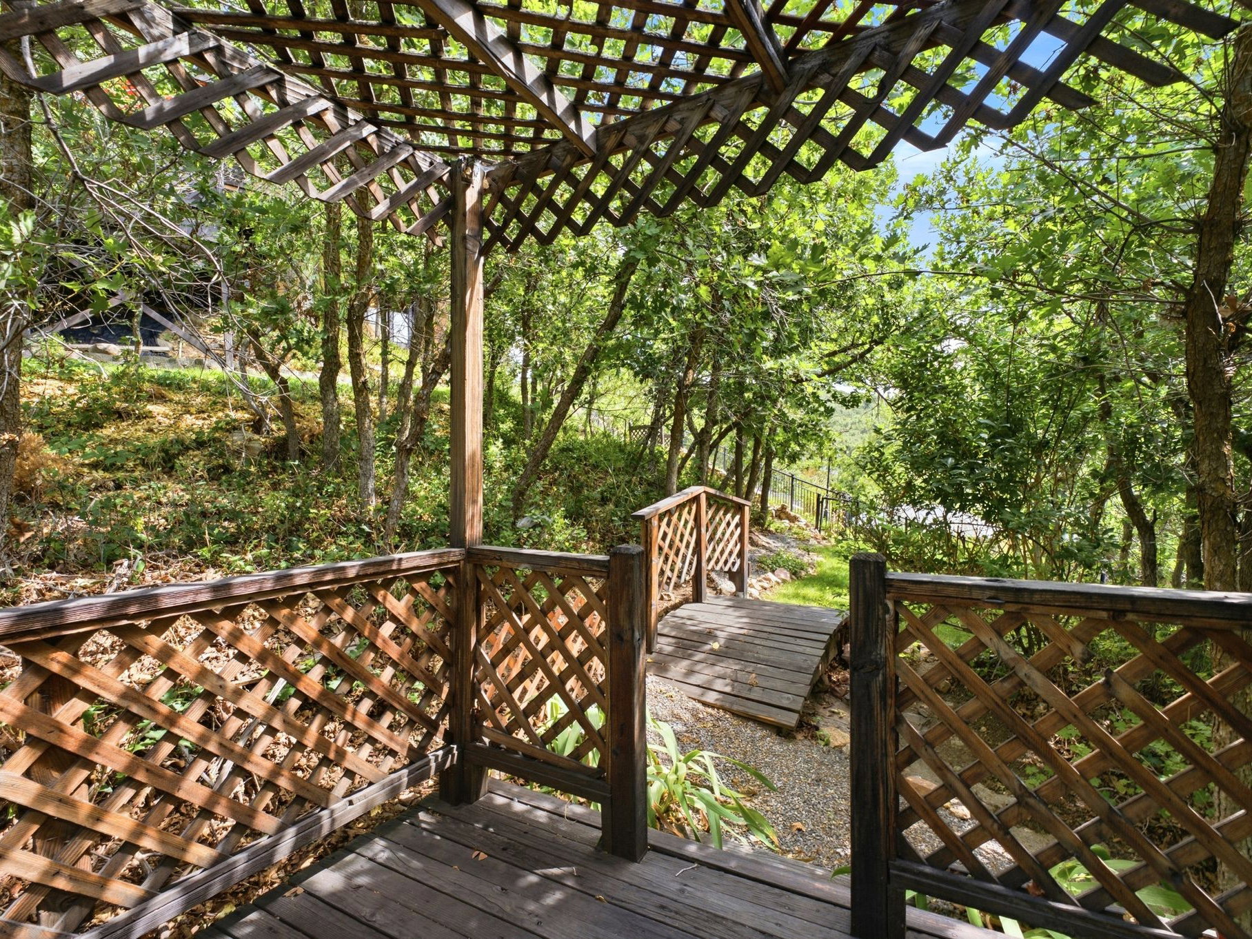 One of the outdoor pergolas featuring a curved wooden bridge and lush surrounding foliage