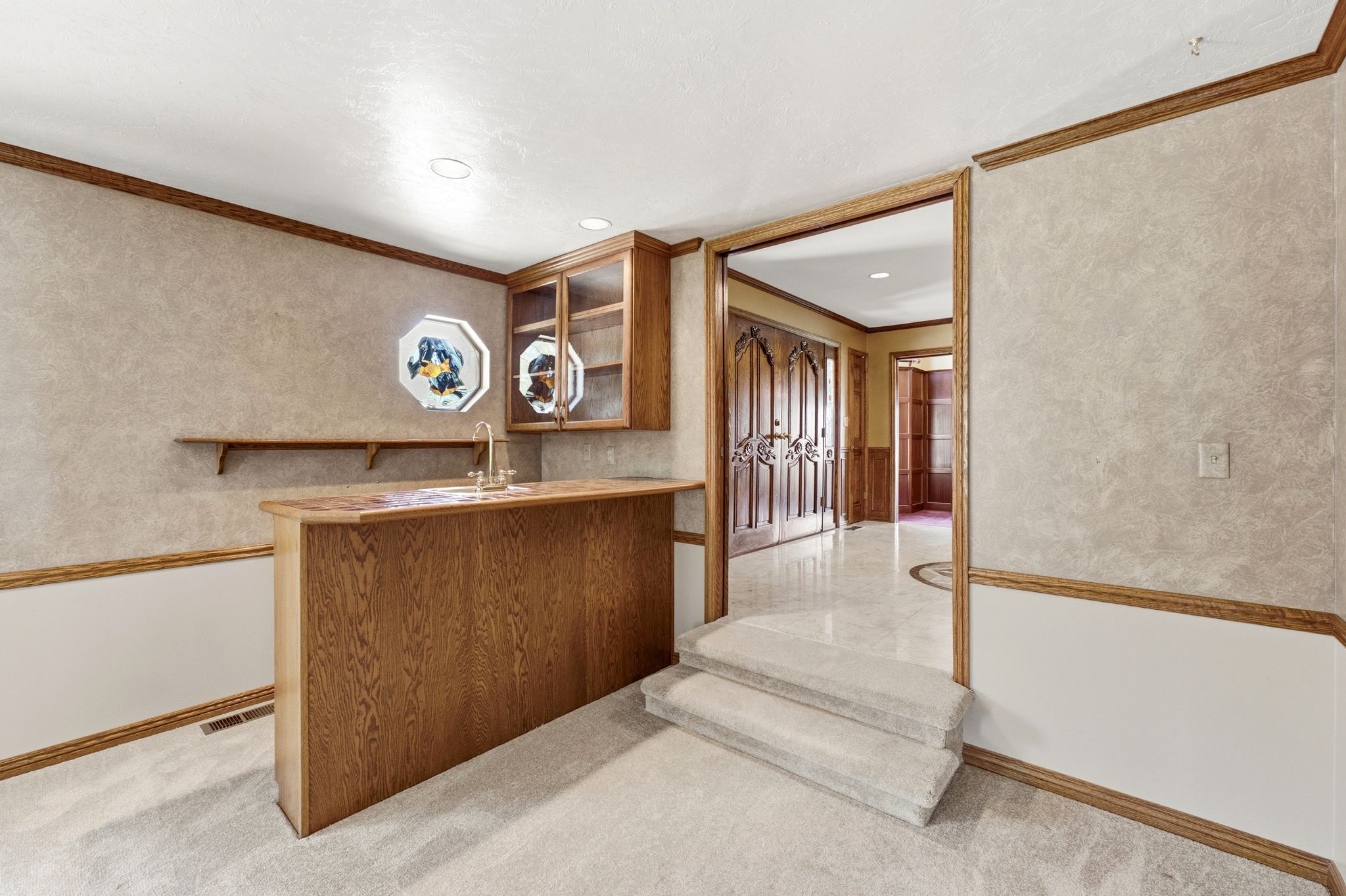 Main level family room built-in wet bar with wood cabinetry and countertop, featuring a sink and faucet