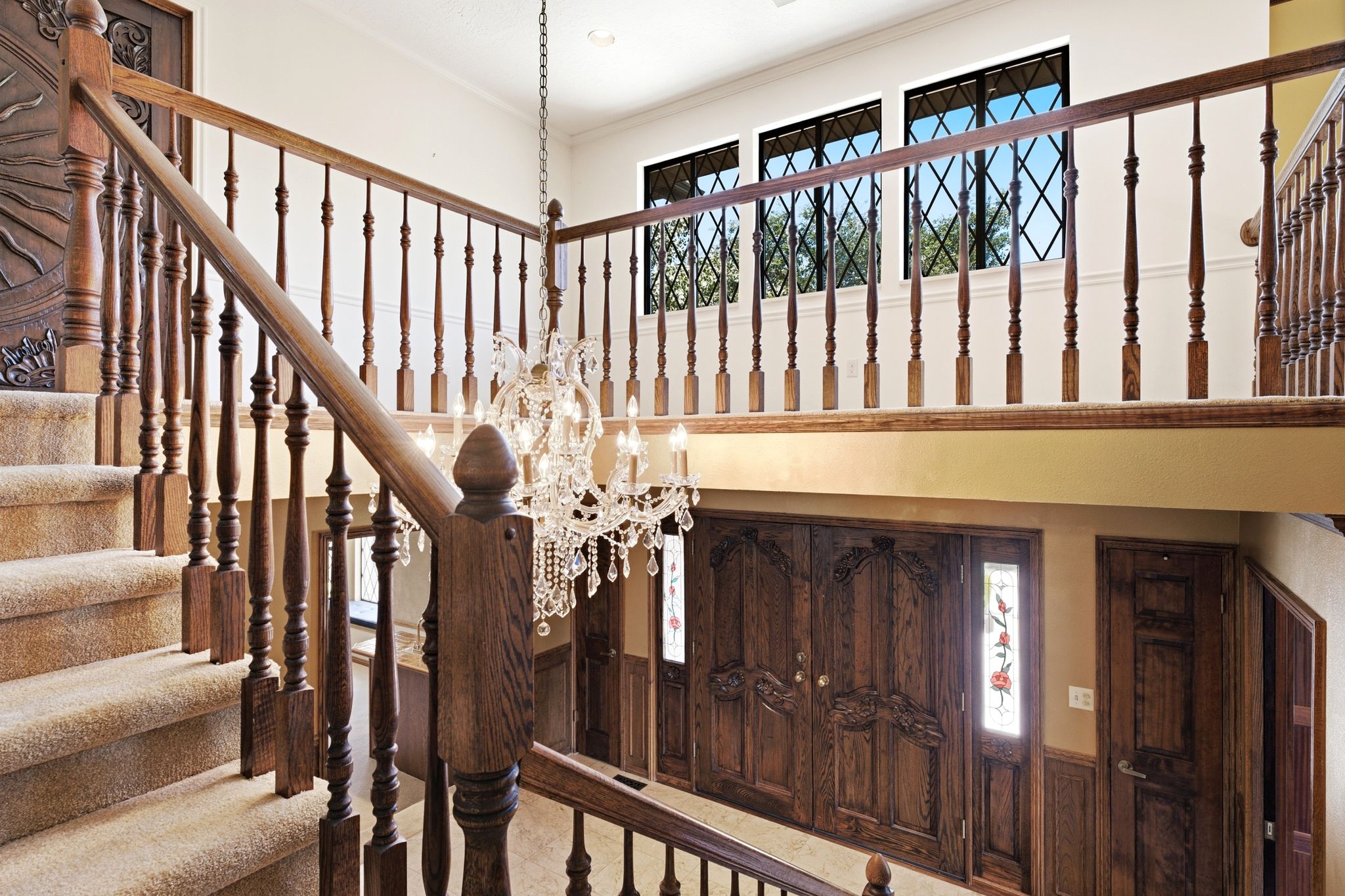 Expansive entry foyer featuring a grand staircase with crystal chandelier and view to upper level