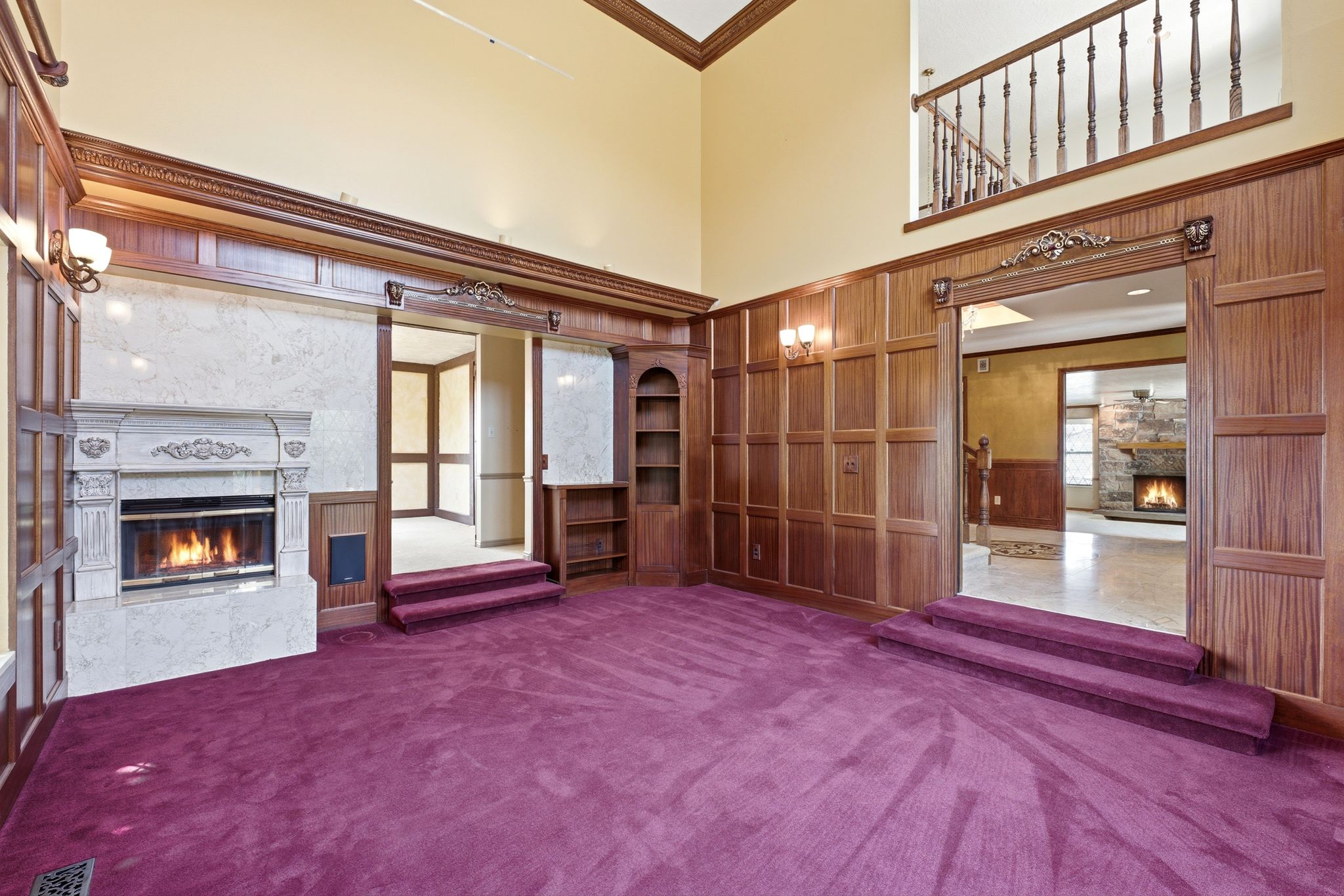 Spacious living room featuring custom wood paneling, a detailed fireplace.