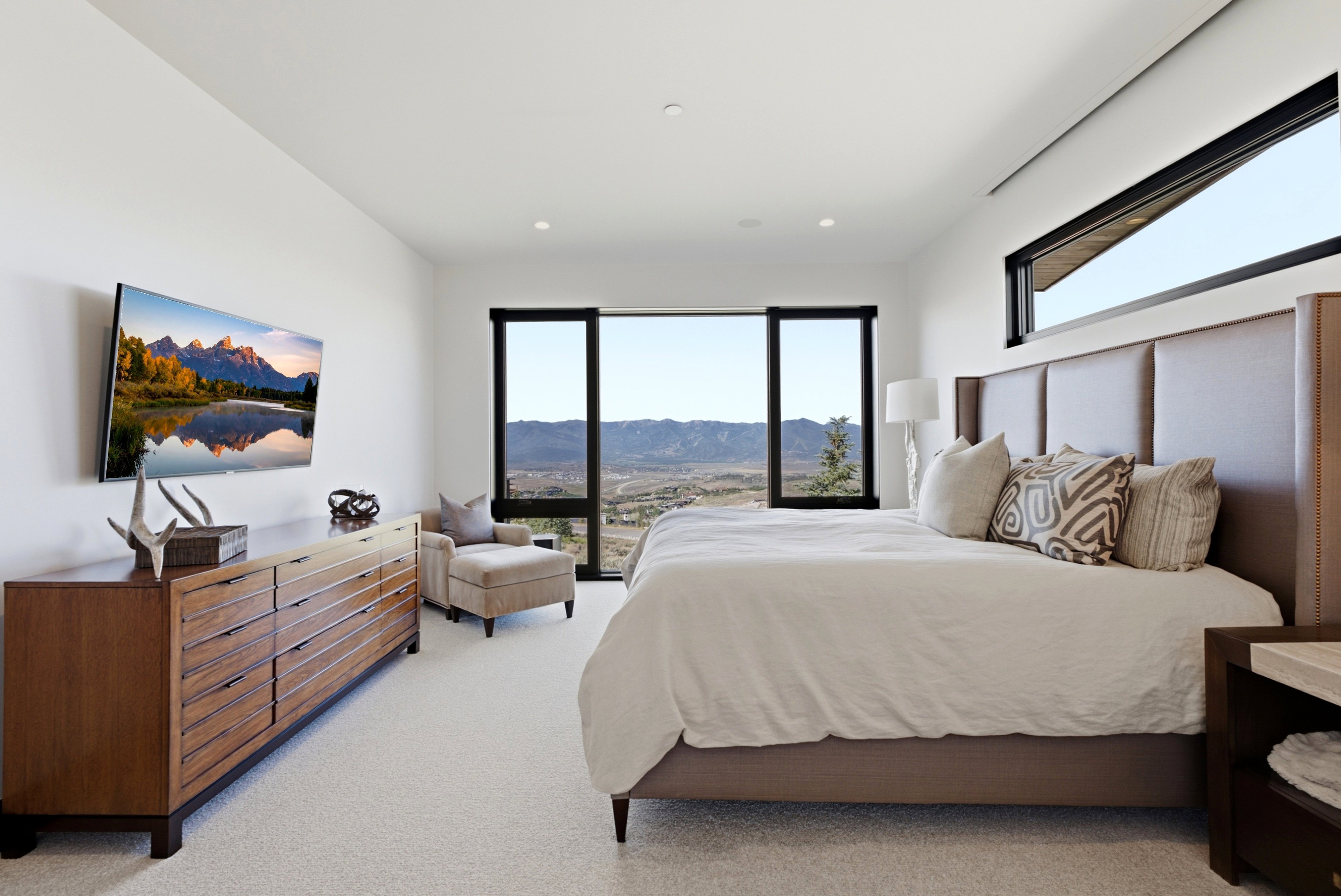 Open-concept room featuring floor-to-ceiling windows, a horizontal transom window, and light-toned carpeting