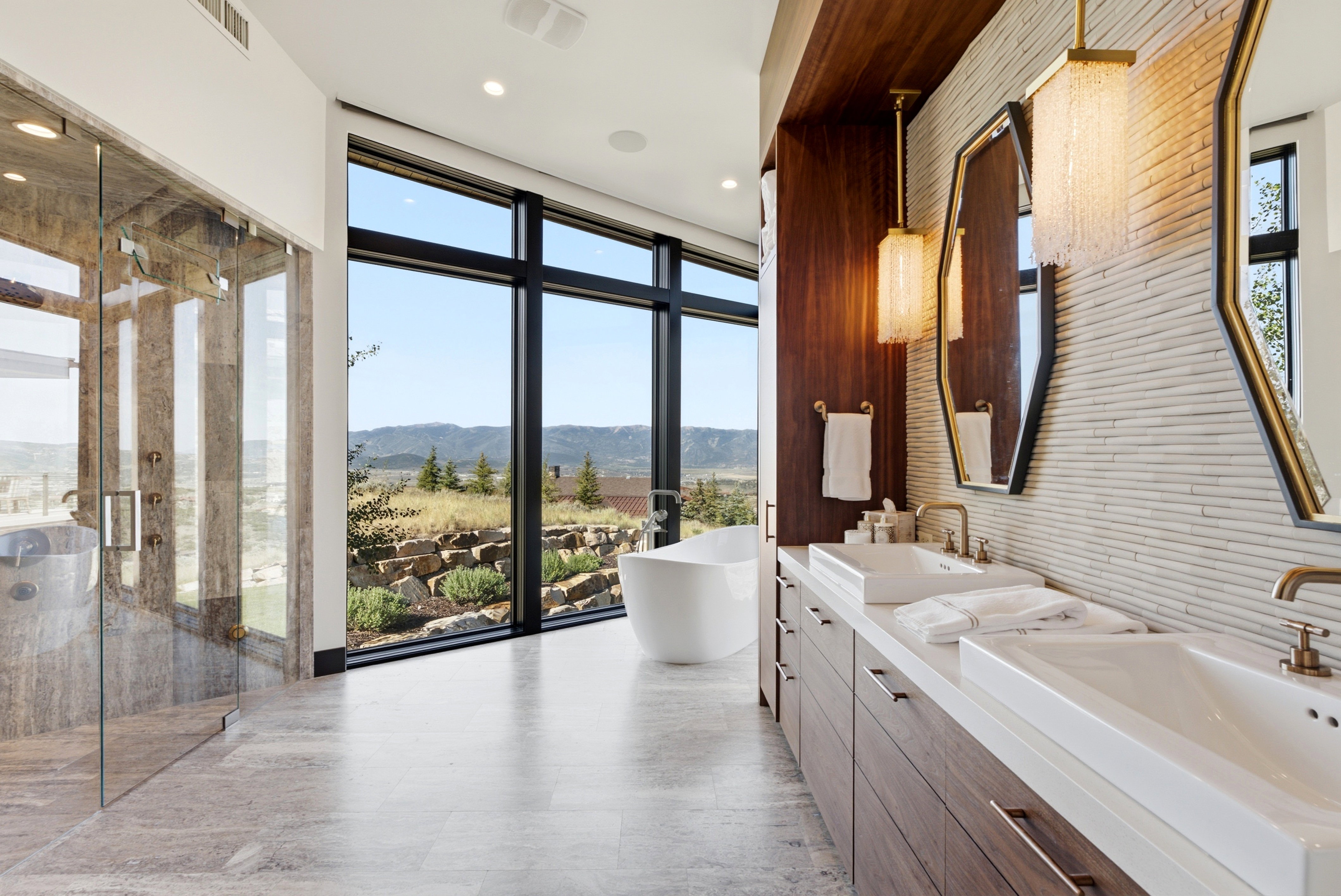 Contemporary bathroom featuring a freestanding tub, expansive picture windows, a glass-enclosed shower, a dual vanity with rectangular vessel sinks, and wood-finish cabinetry