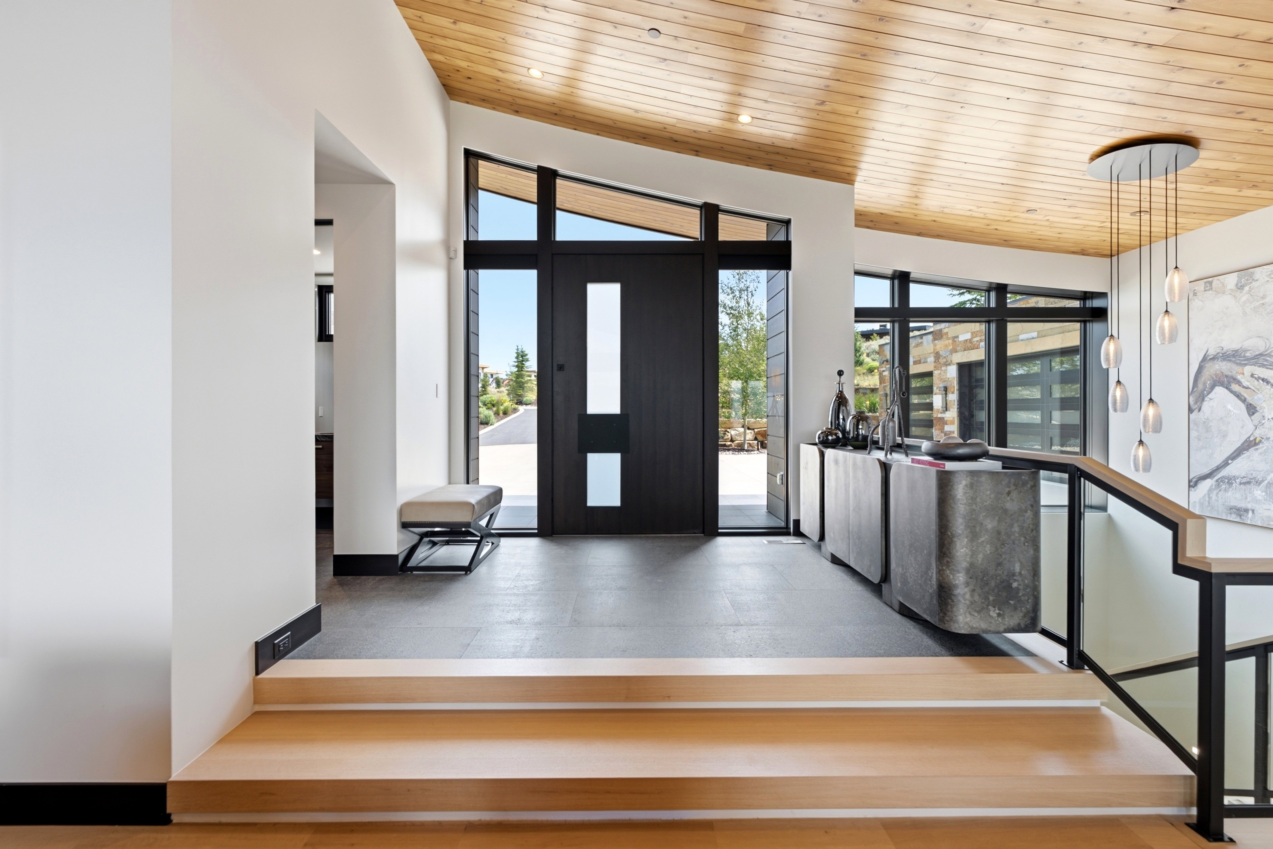 Grand entry featuring a dark wood door with glass inserts, transom windows, and a vaulted wood-paneled ceiling