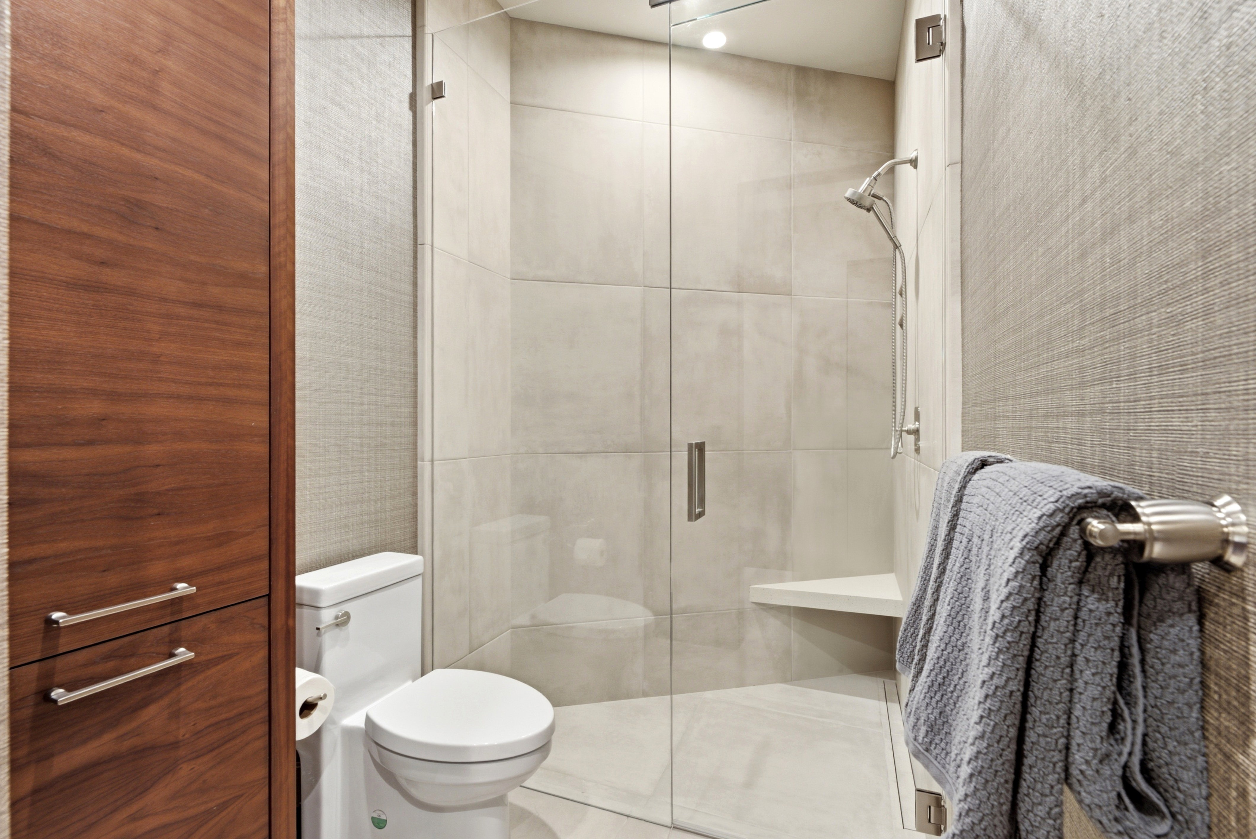 Modern bathroom featuring a glass-enclosed shower with large format tile, a built-in shower bench, and a brushed nickel showerhead