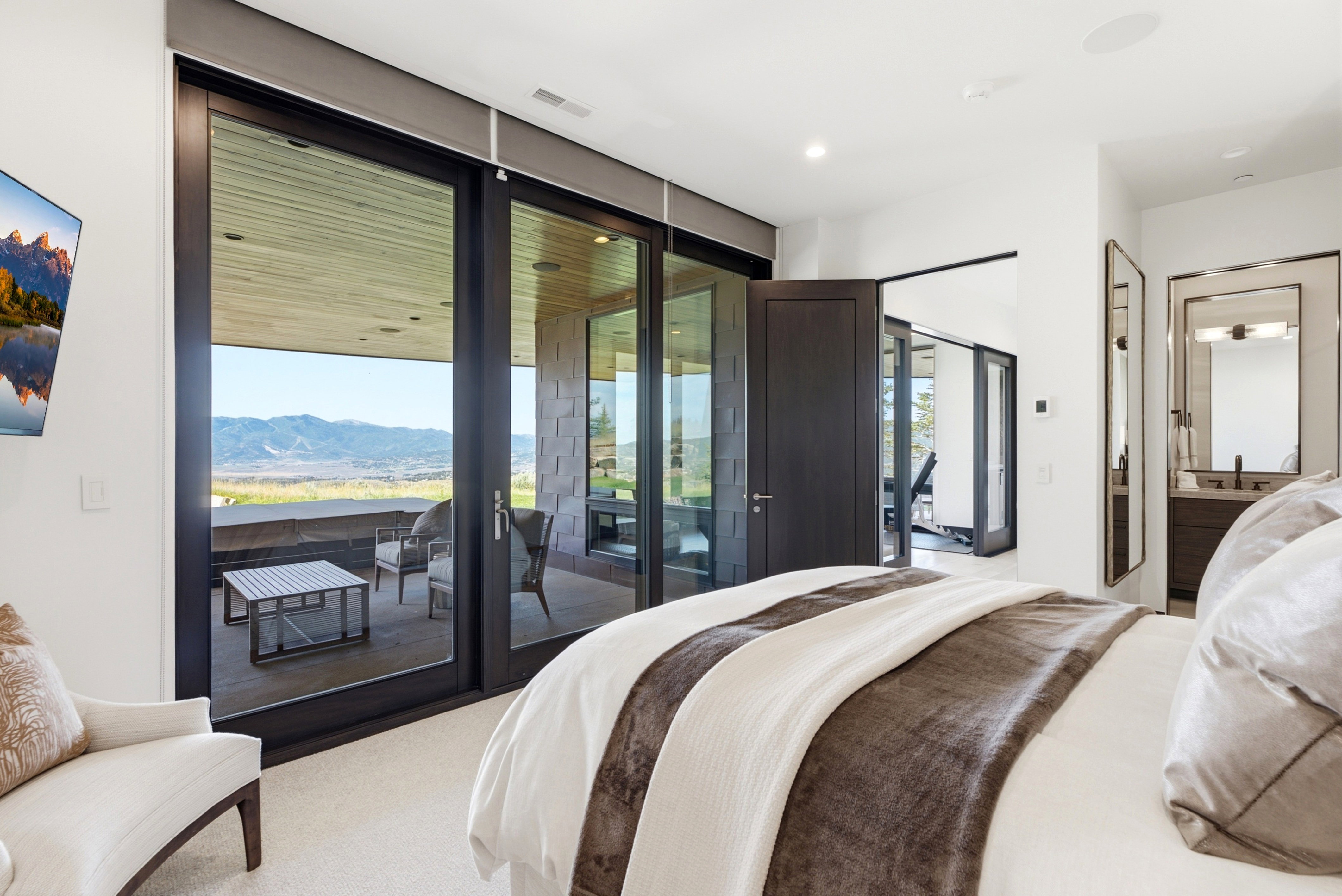 Bedroom featuring expansive sliding glass doors opening to an outdoor patio with mountain scenery