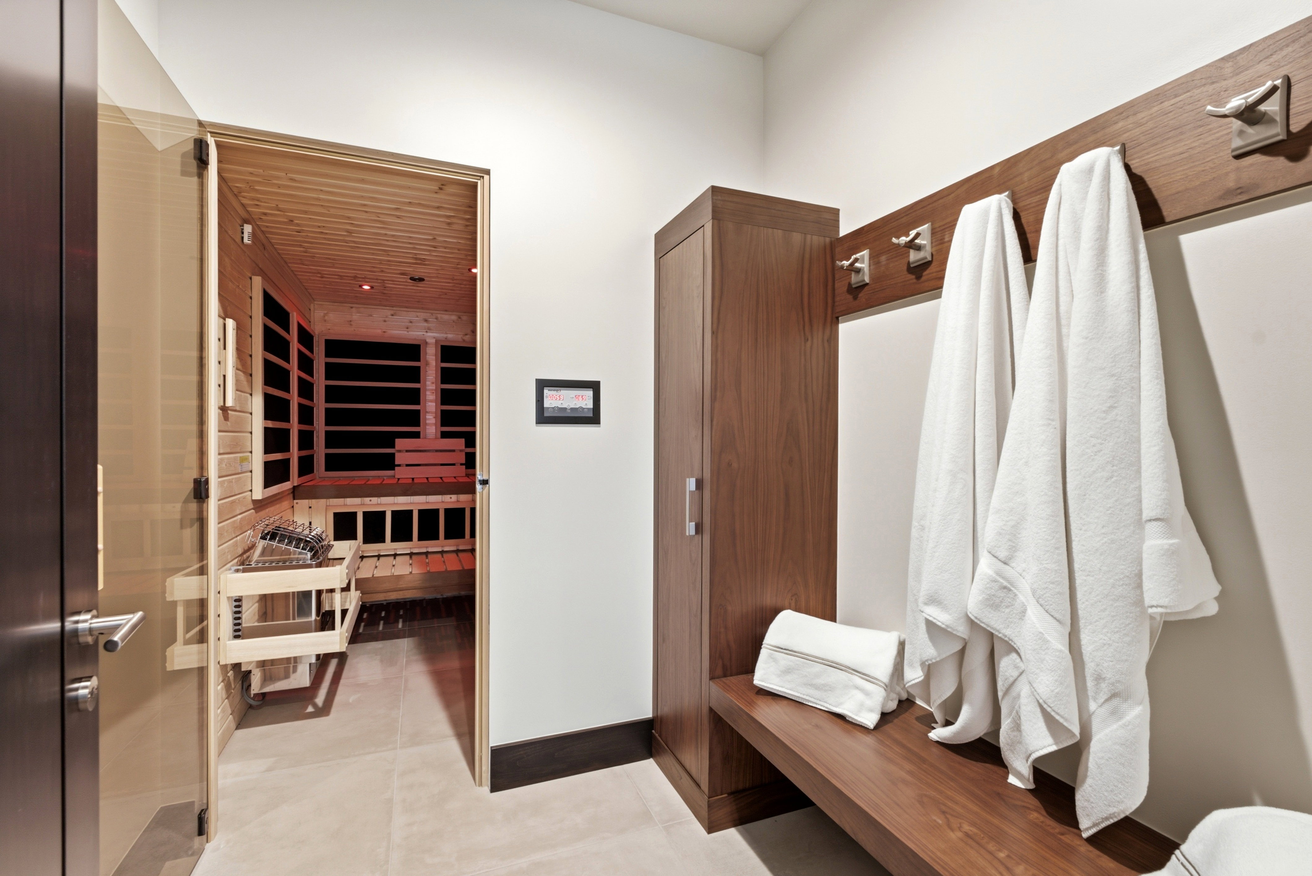 Dedicated sauna room featuring a light wood interior, built-in wooden benches, and an integrated heater