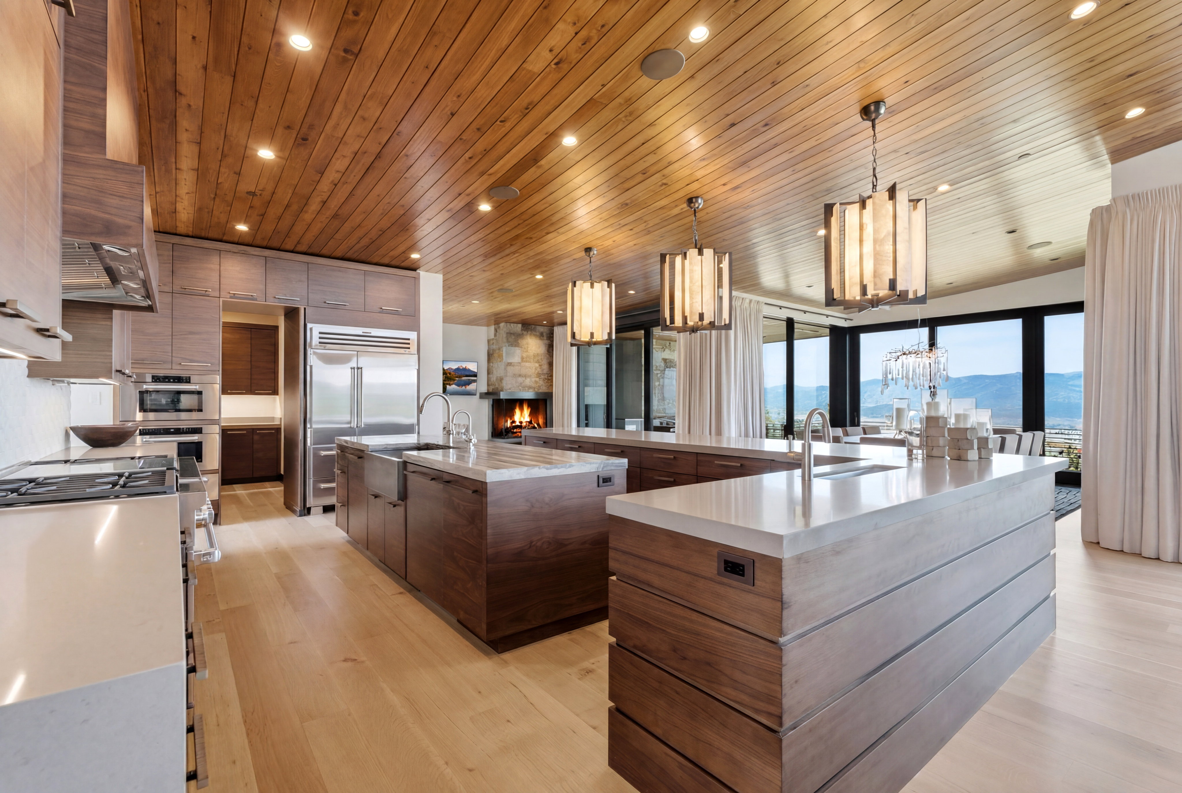 Gourmet kitchen featuring a wood-panel ceiling with recessed lighting, light wood-finish flooring, and multiple islands with sinks